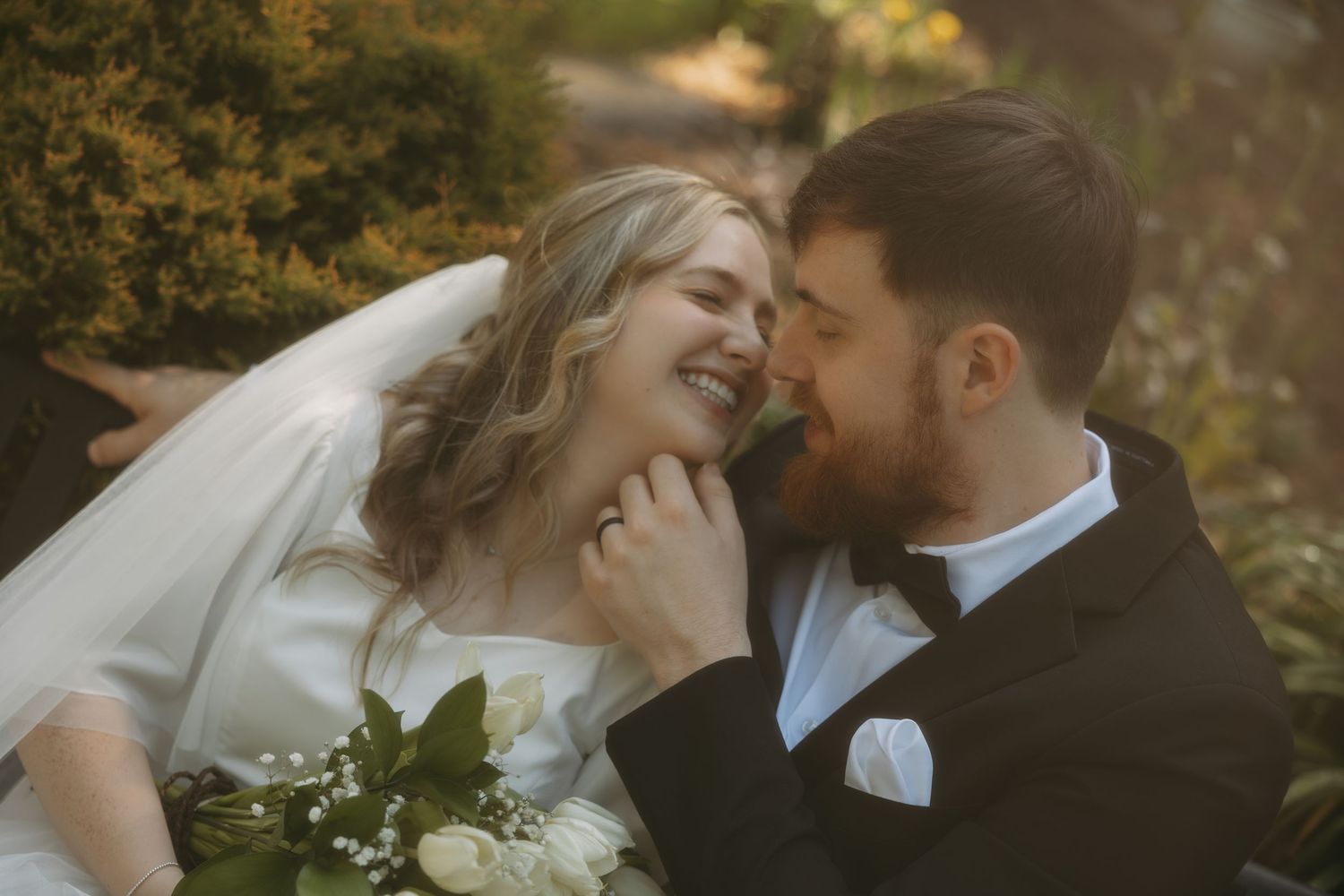 Joyful bride and groom share an intimate moment laughing together outdoors among golden foliage.
