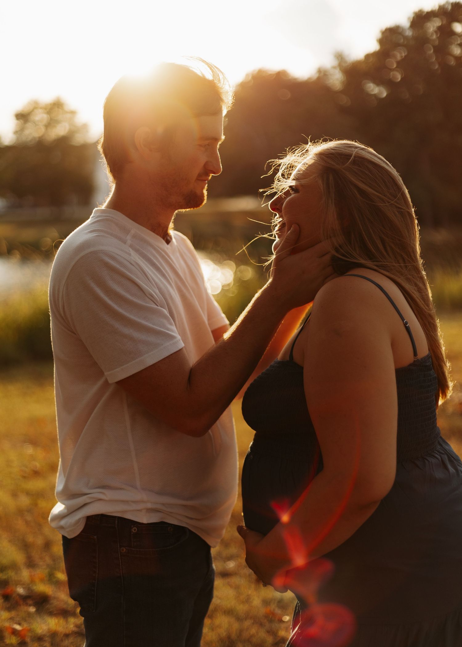 Loving couple shares joyful moment together in golden sunlight during outdoor photoshoot at sunset.