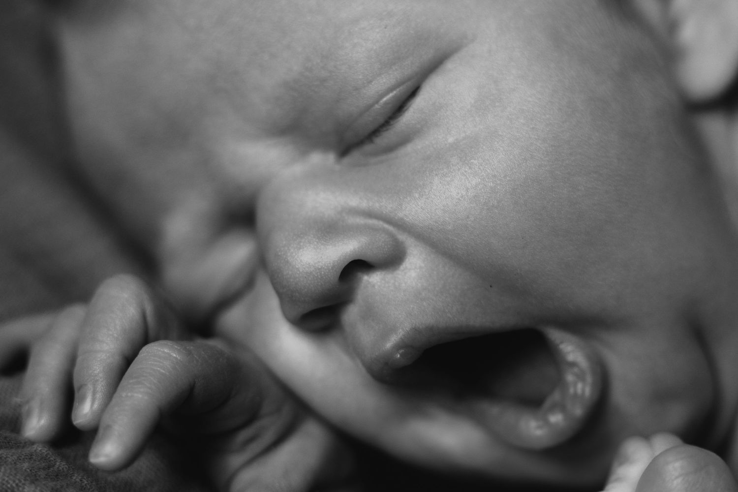 Close-up black and white image of a crying infant in an emotional moment.