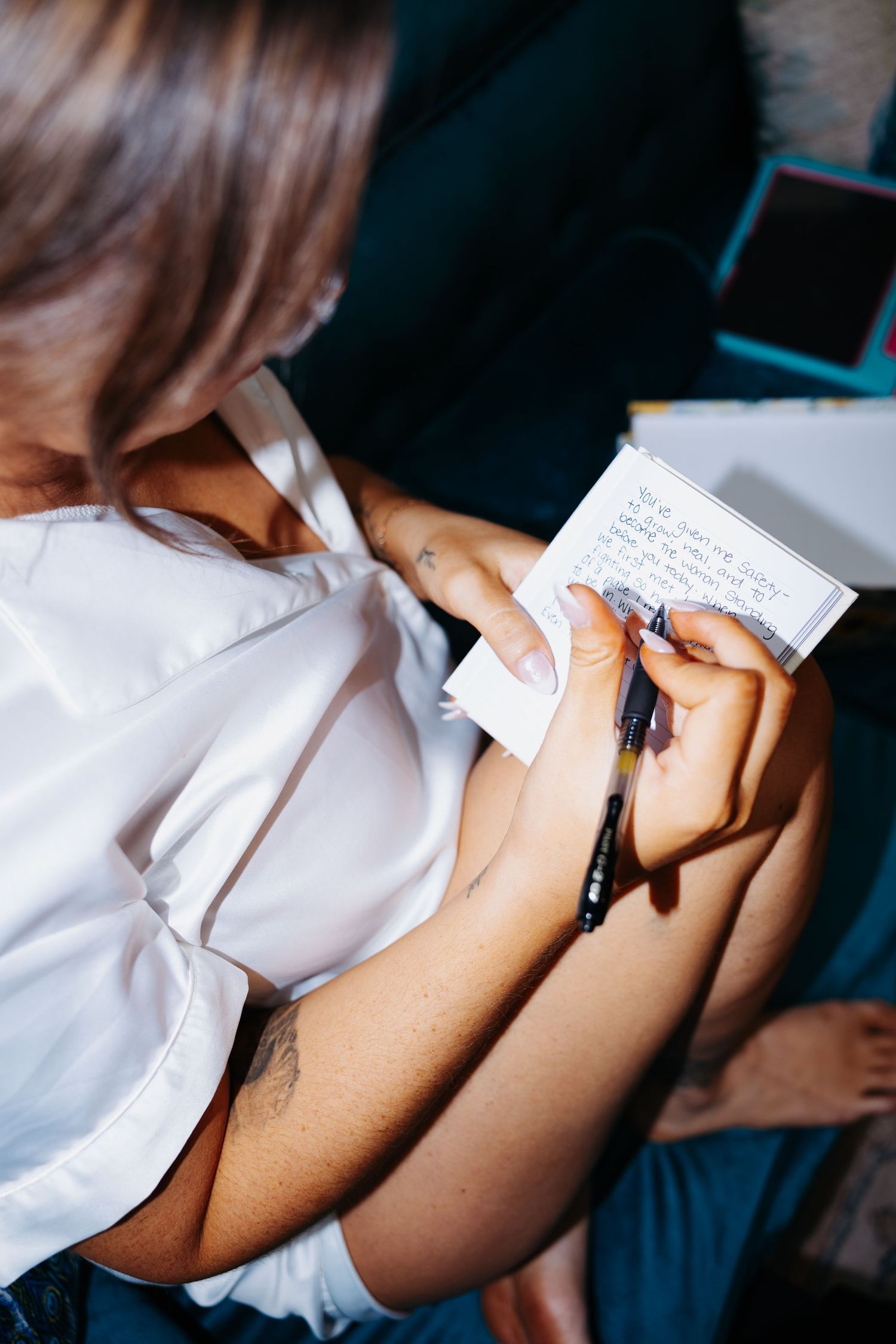 Woman in white shirt writing notes on a small card with a pen.