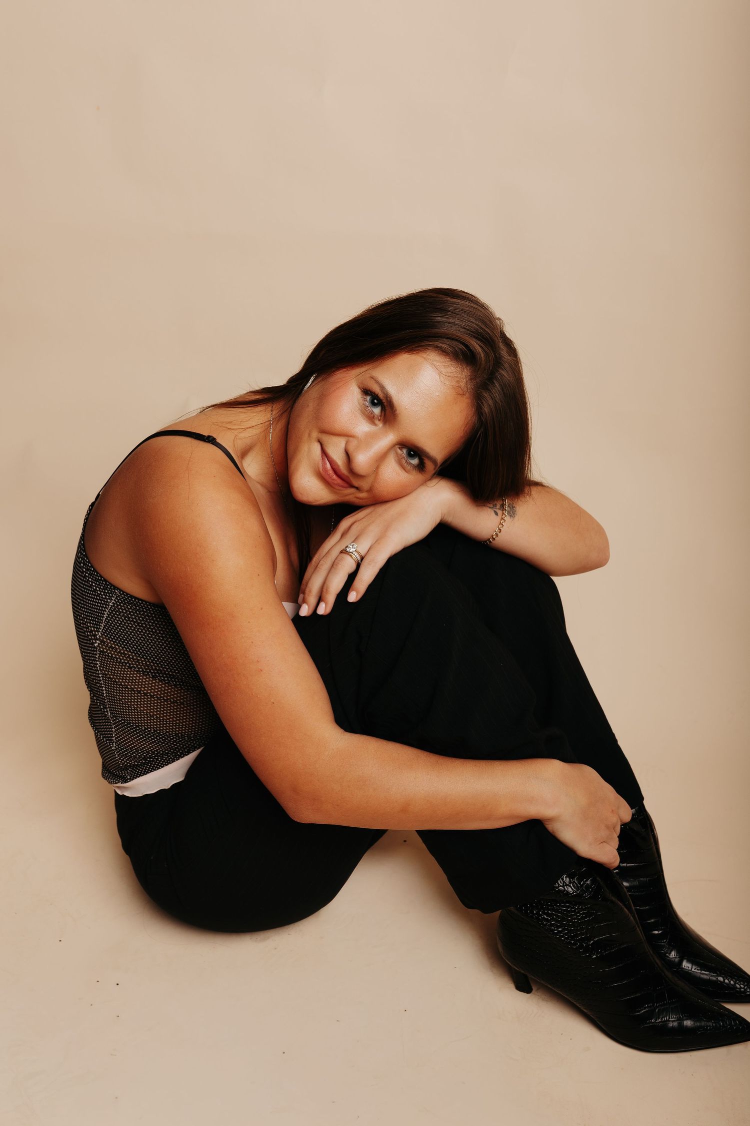 Artistic photo series showing a woman in black attire reclining in different poses against a beige backdrop.