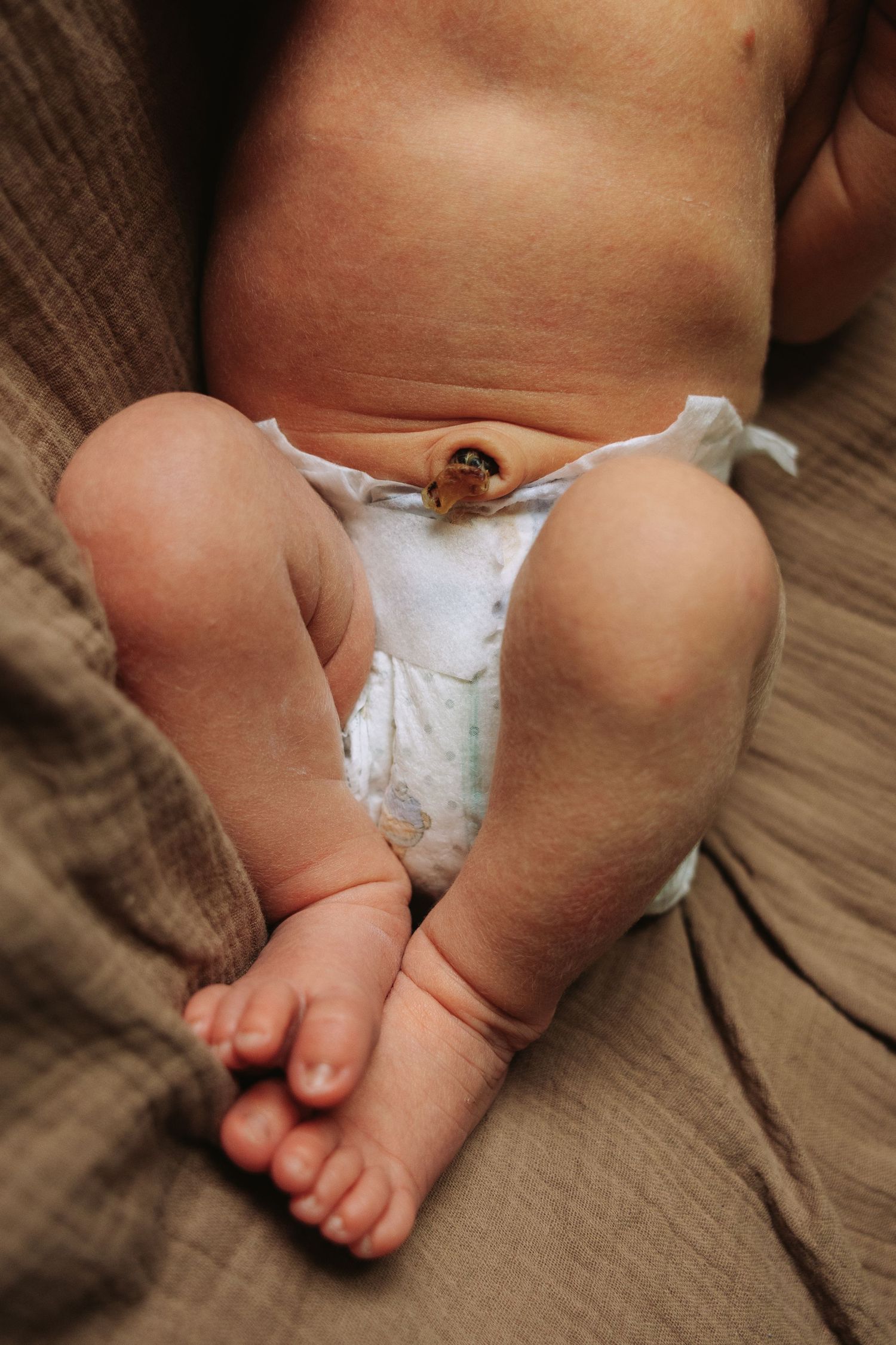 Small baby feet with white diaper and blanket shown in sequence on a soft brown surface.