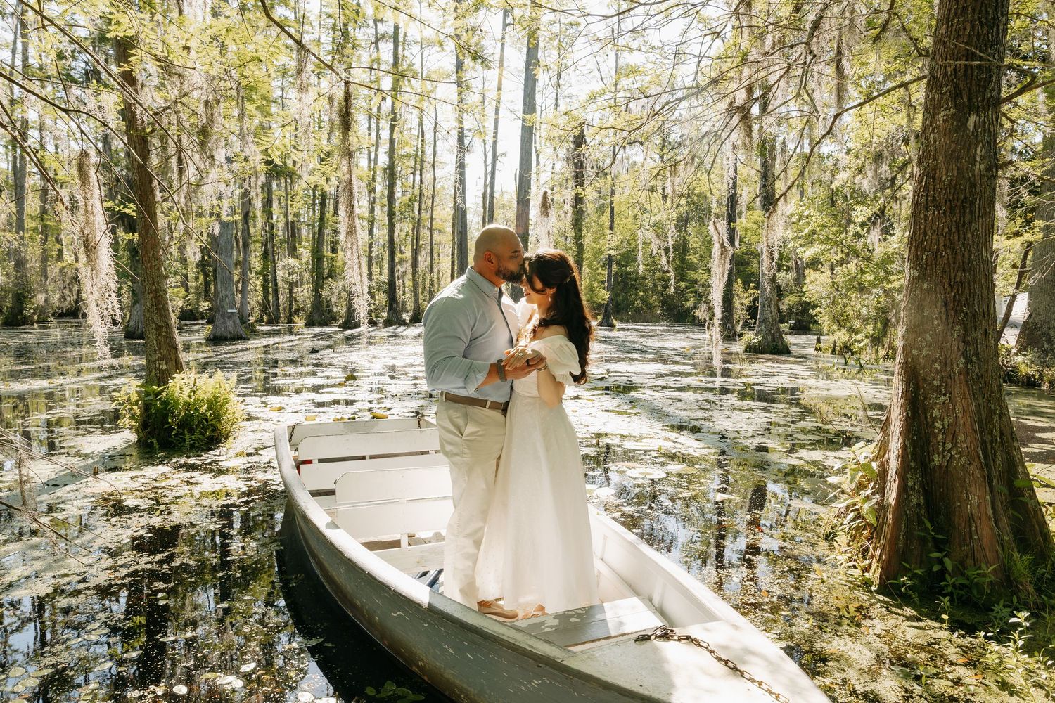 Couple sharing a romantic embrace in a canoe surrounded by a lush cypress swamp forest.