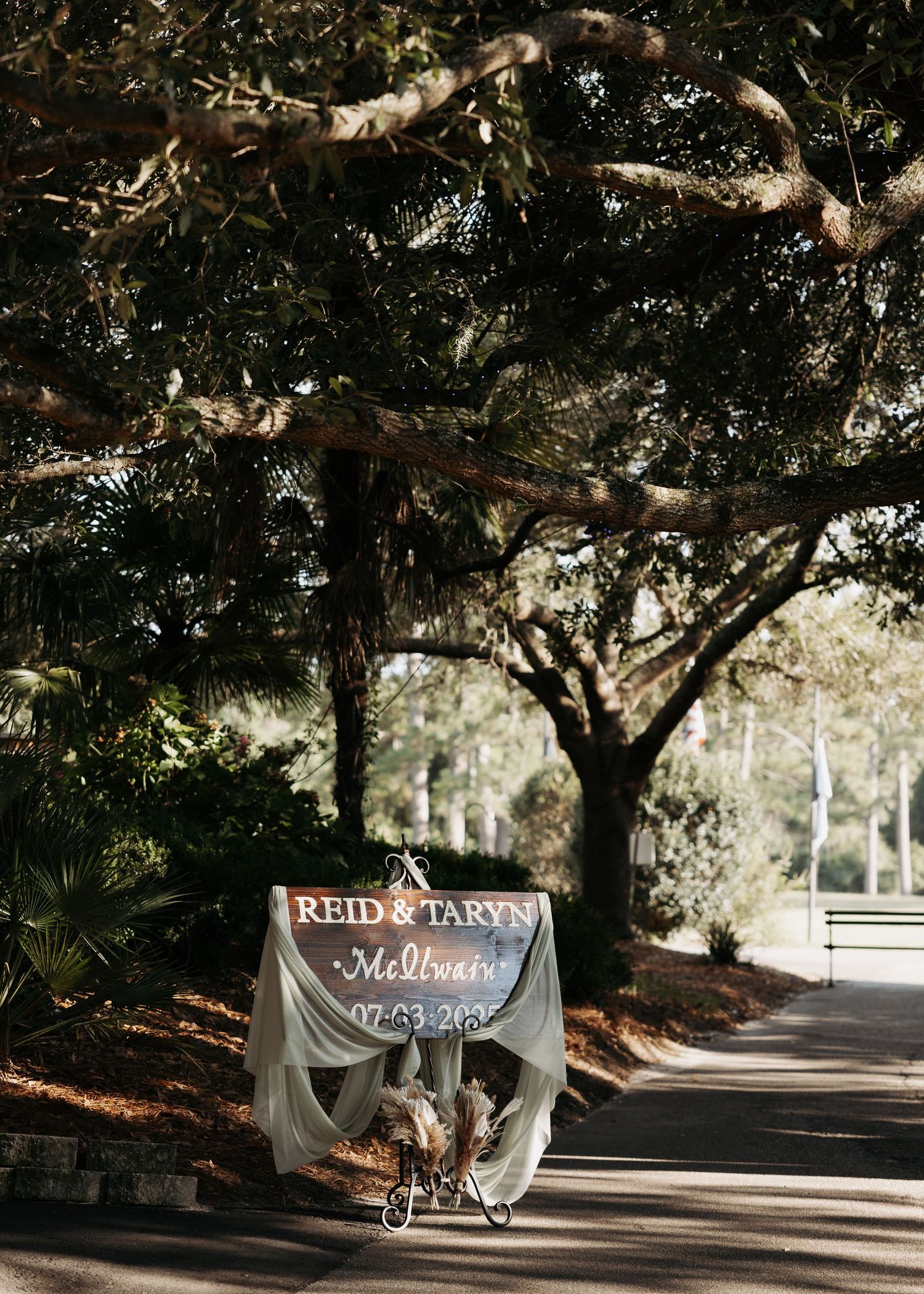 Rustic wedding welcome sign for Reid and Taryn displayed under sprawling oak trees at Melbourne venue dated 07-03-2023.