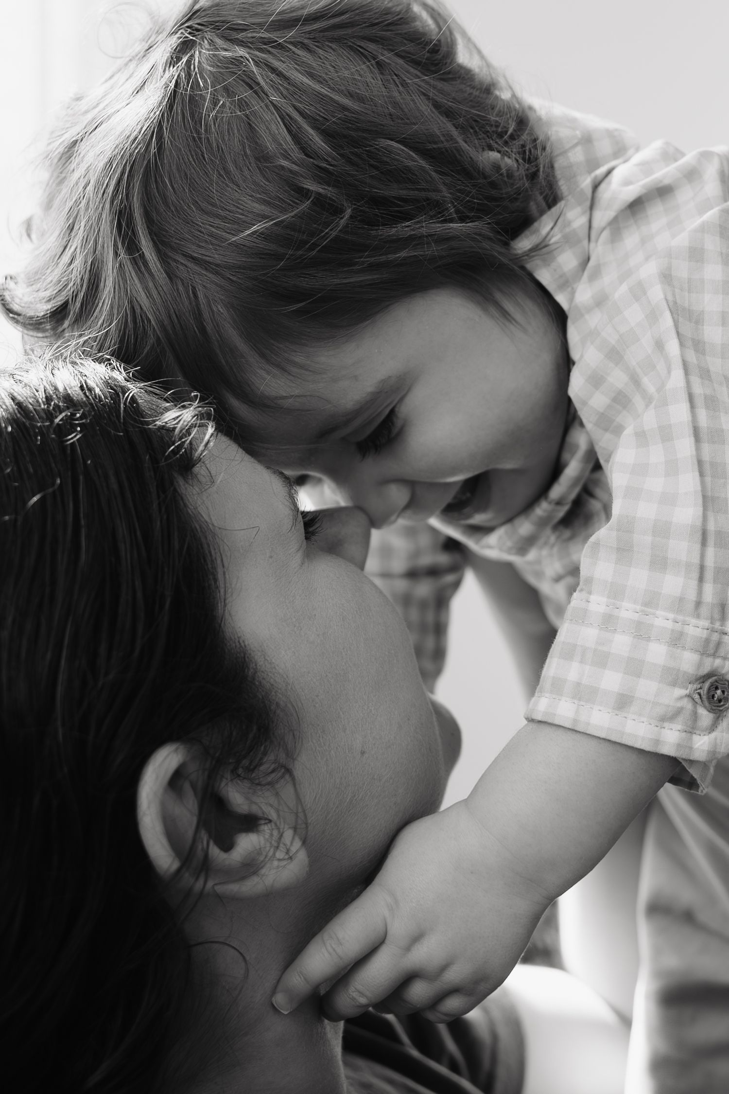 Black and white photo of a mother lovingly holding her laughing toddler close, touching foreheads in a tender moment.