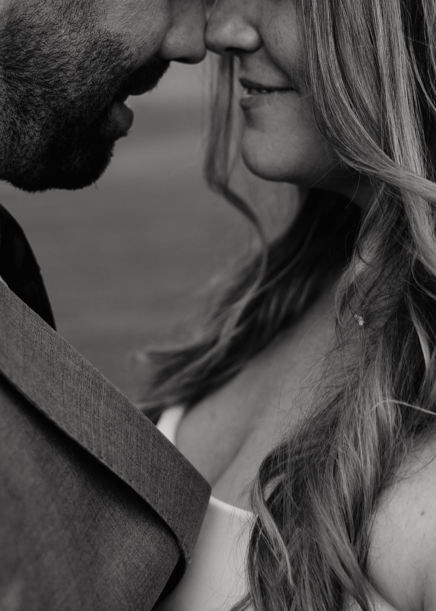Black and white close-up of a bride and groom sharing a tender almost-kiss on their wedding day.