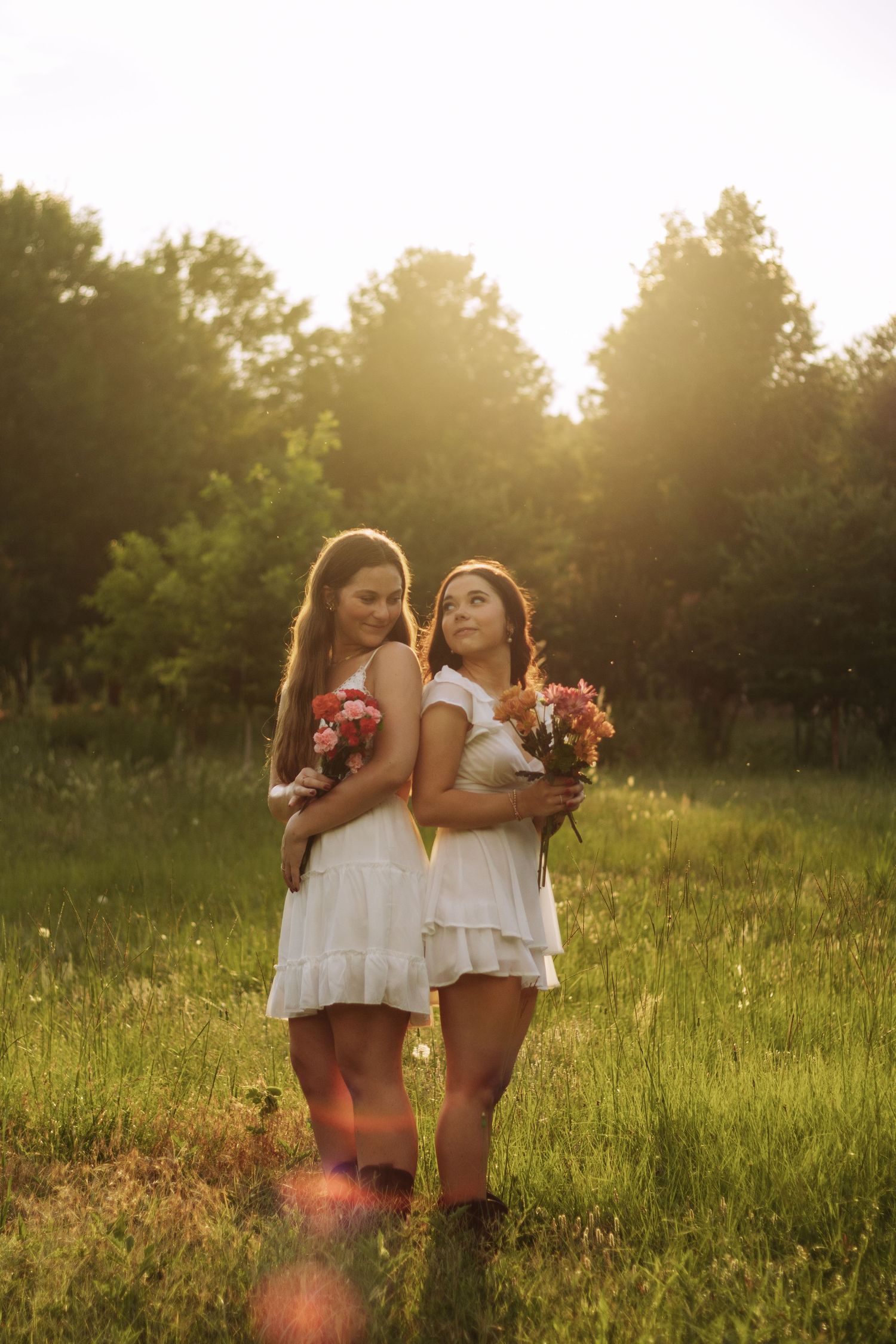 Two children share a tender moment at sunset in a meadow filled with wildflowers and warm golden light.