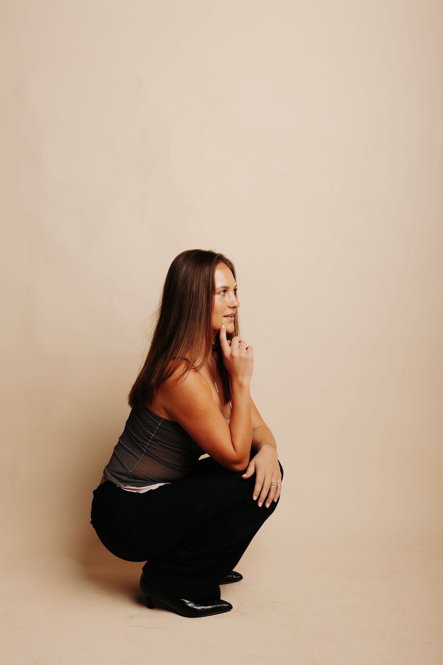 A series of minimalist portraits showing someone in black clothing crouched against a beige background.