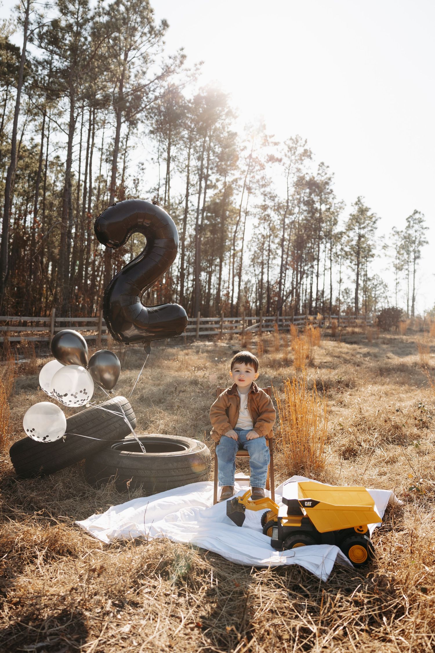A cozy winter picnic setup in a forest with blankets, hot drinks and warm attire against a sunlit woodland backdrop.