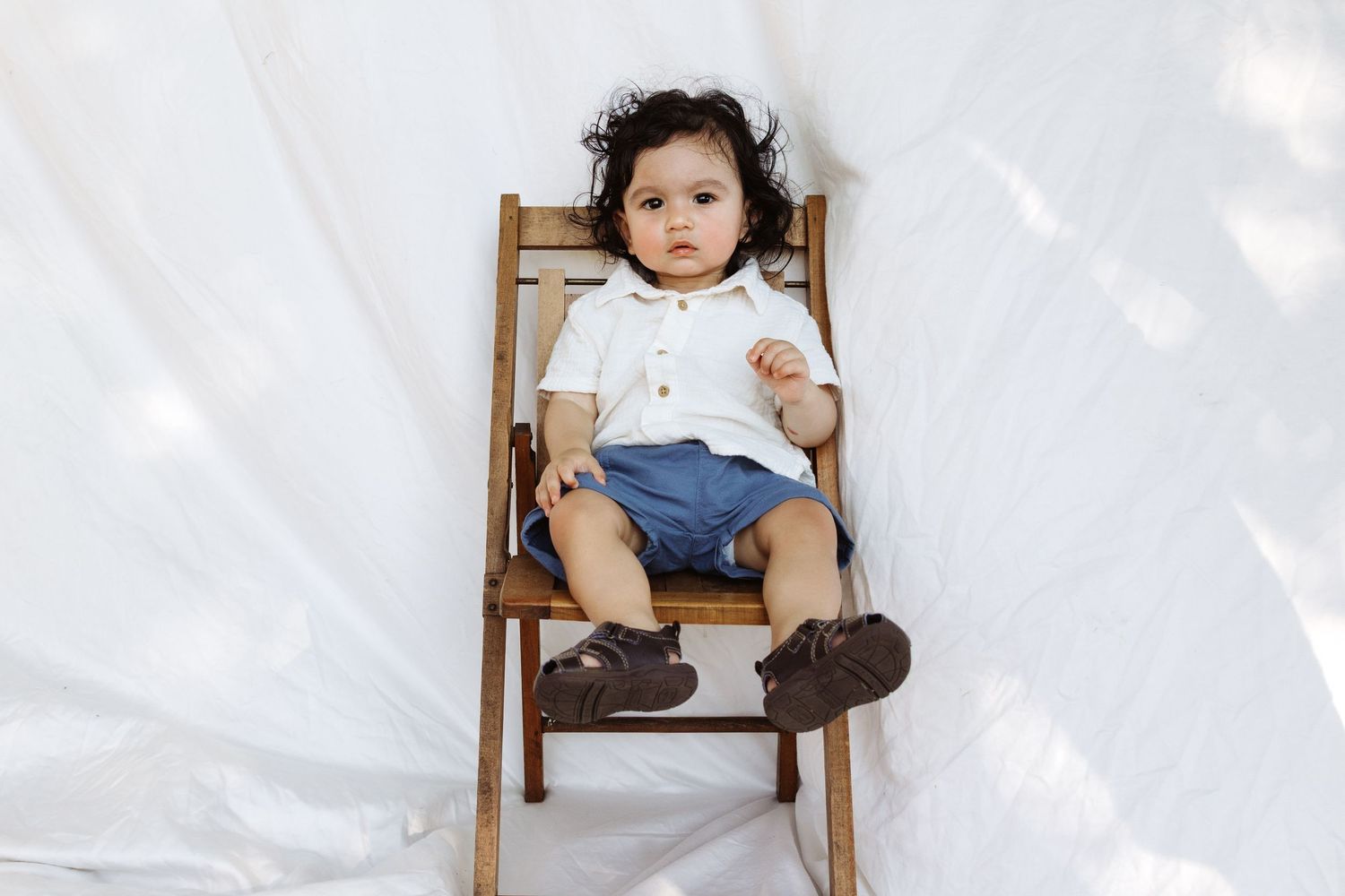 Child sitting in wooden chair series against white background.