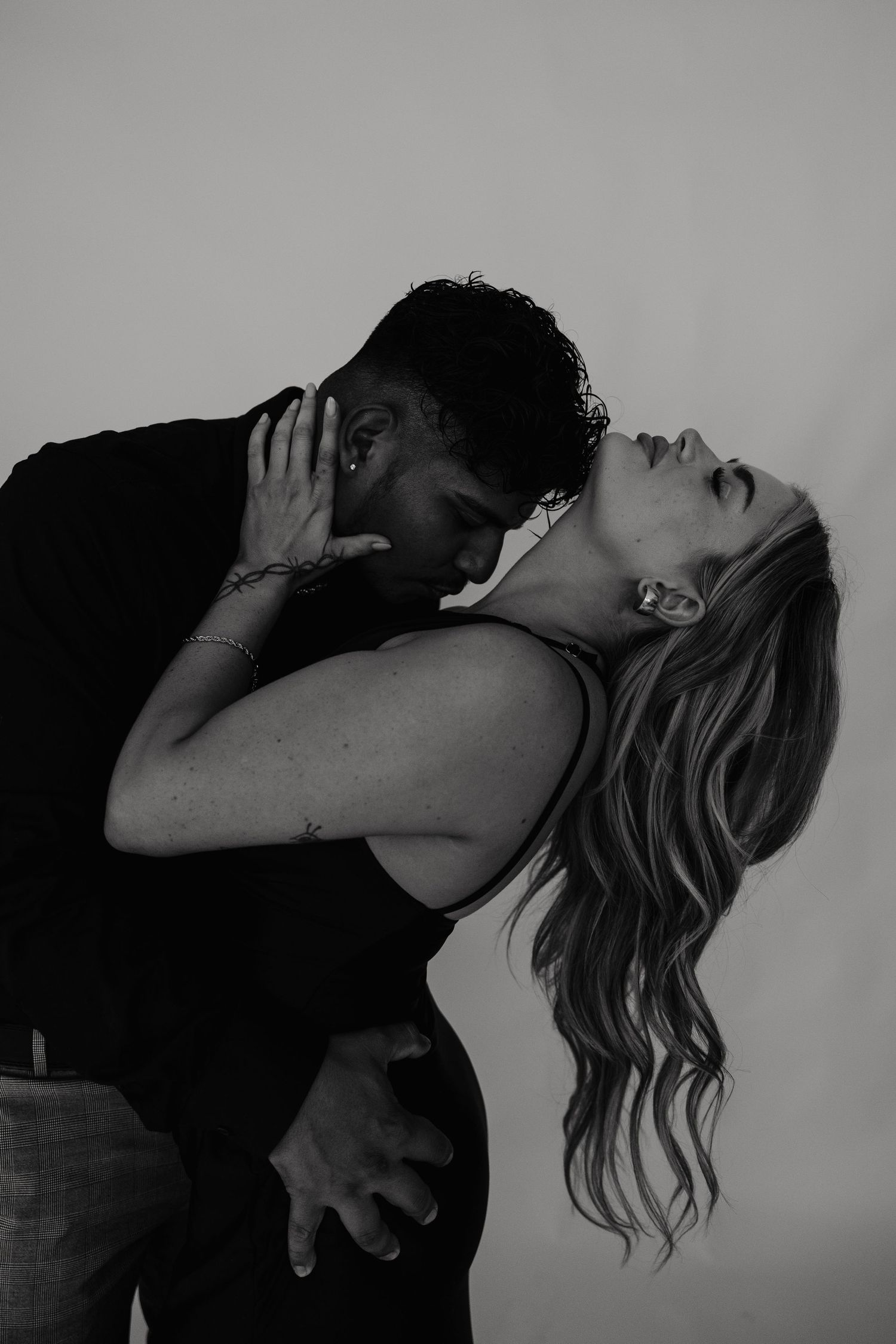 Black and white photo of a couple sharing a passionate kiss, woman leaning back with flowing hair.
