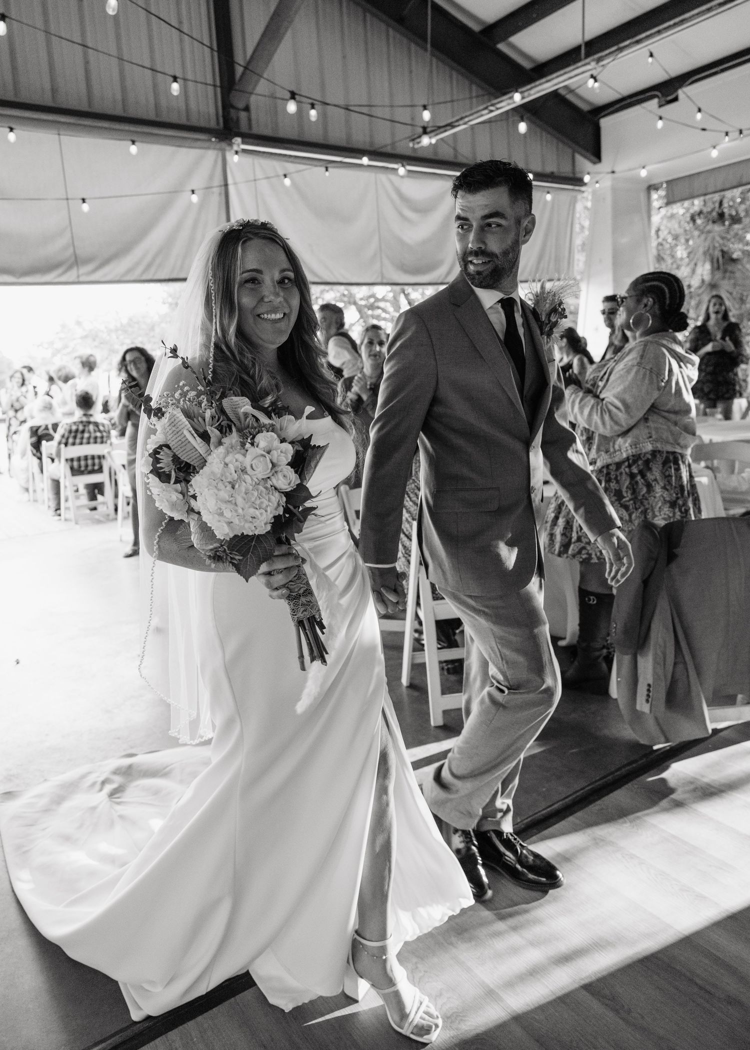 Bride and groom walk back down aisle after ceremony in black and white wedding photo.