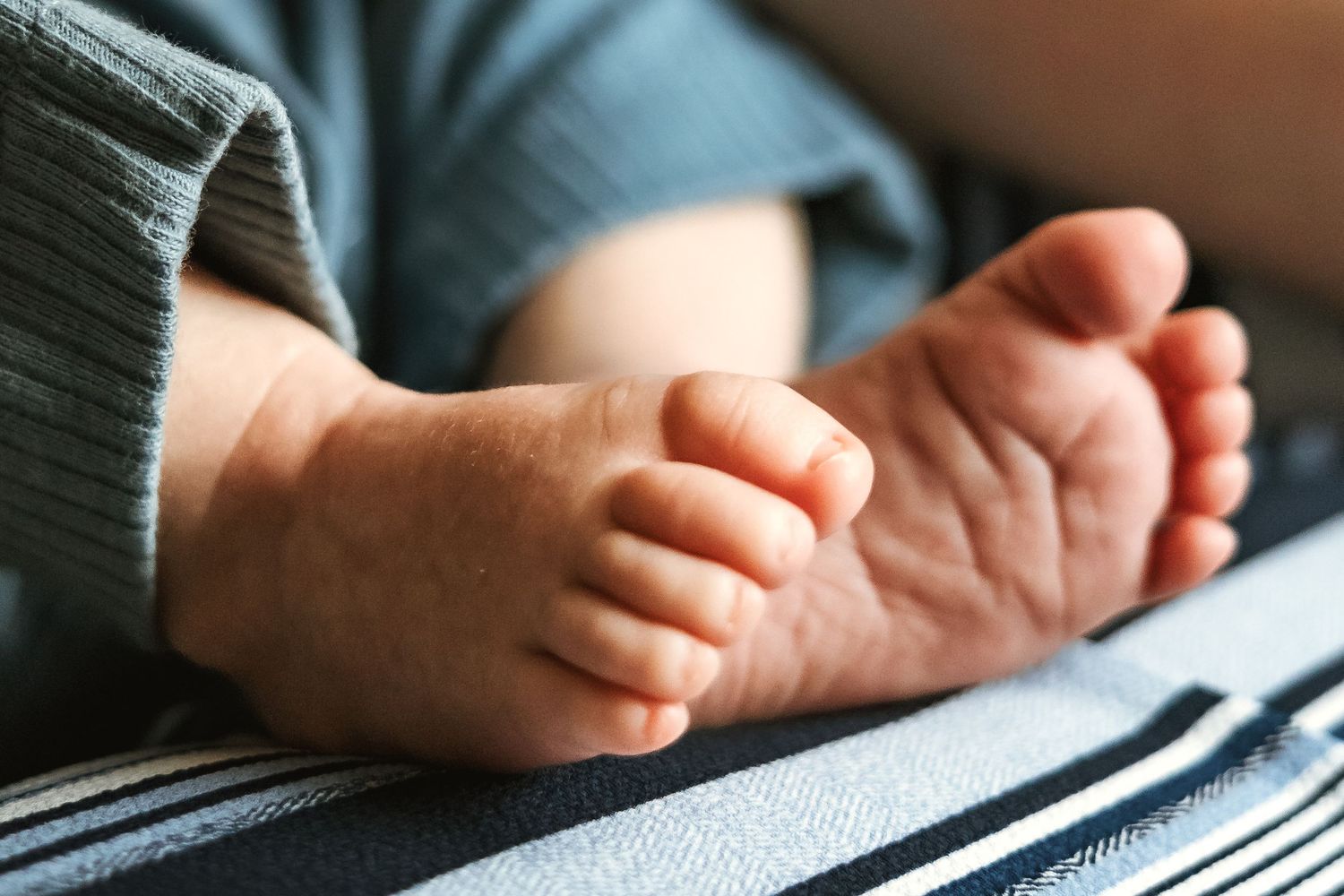 Baby's tiny feet and toes against striped fabric.