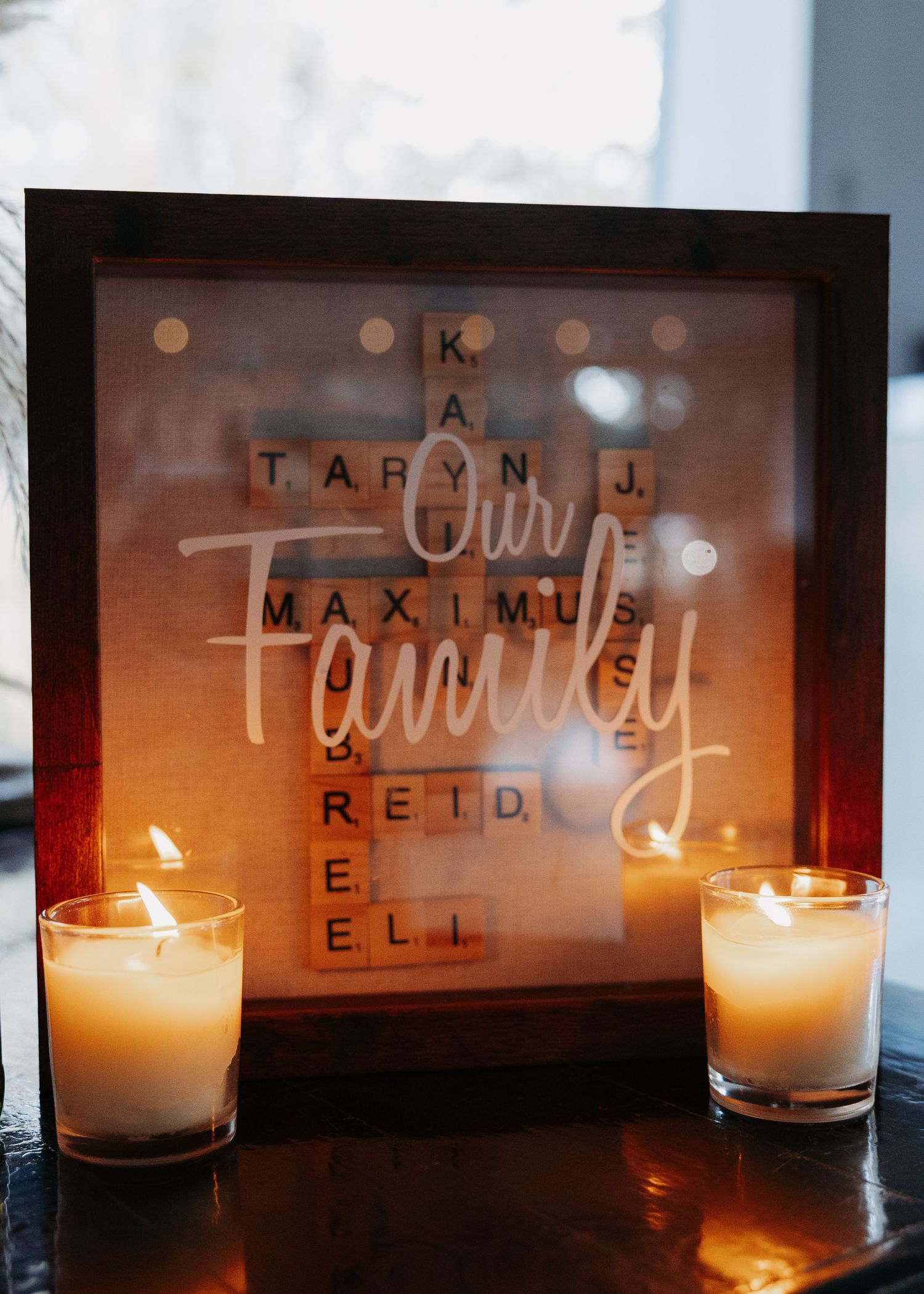 Illuminated Scrabble tile family name shadow box with candles displaying Our Family wedding decor.