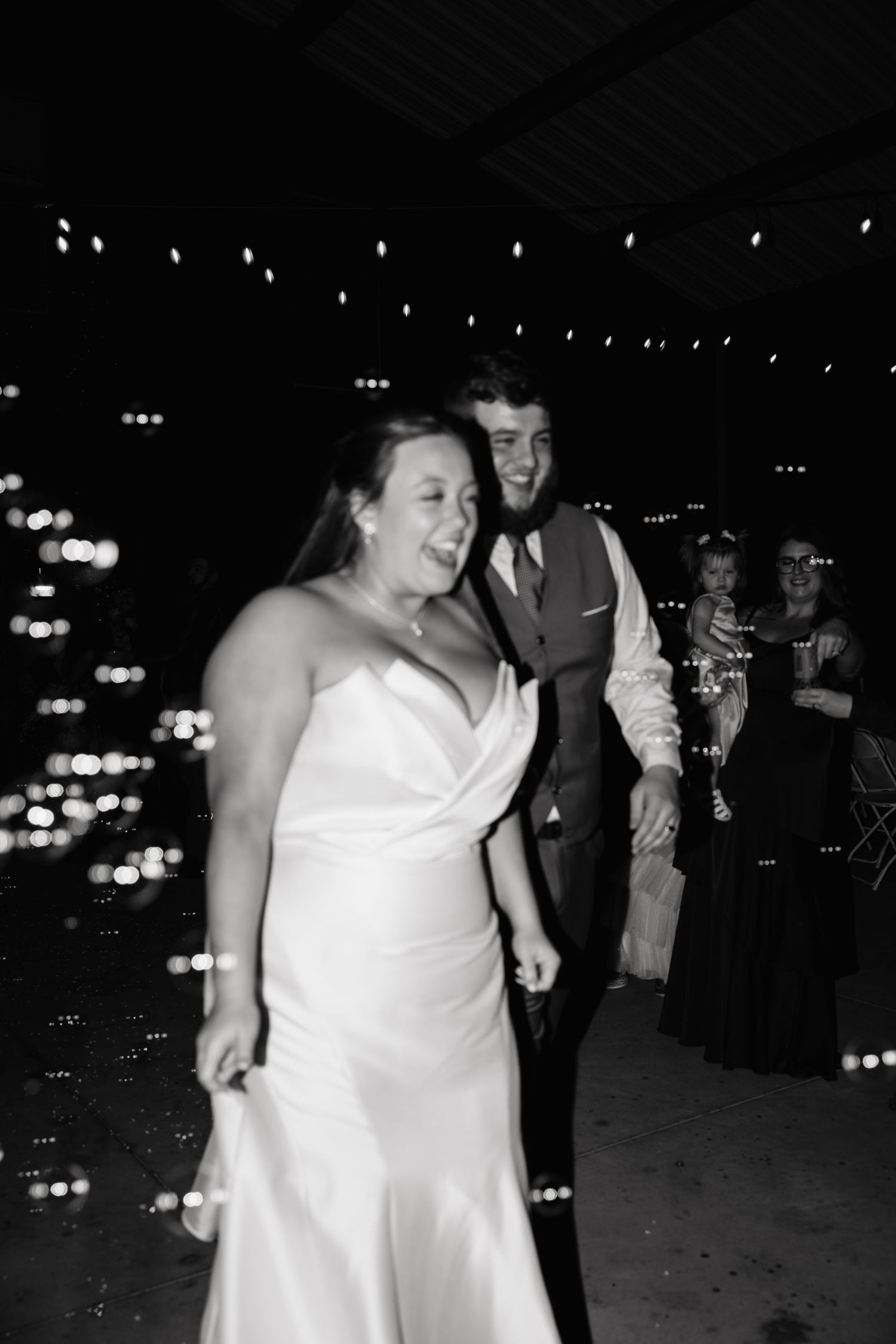Bride and groom sharing a joyful first dance moment in black and white photo at their evening wedding reception.