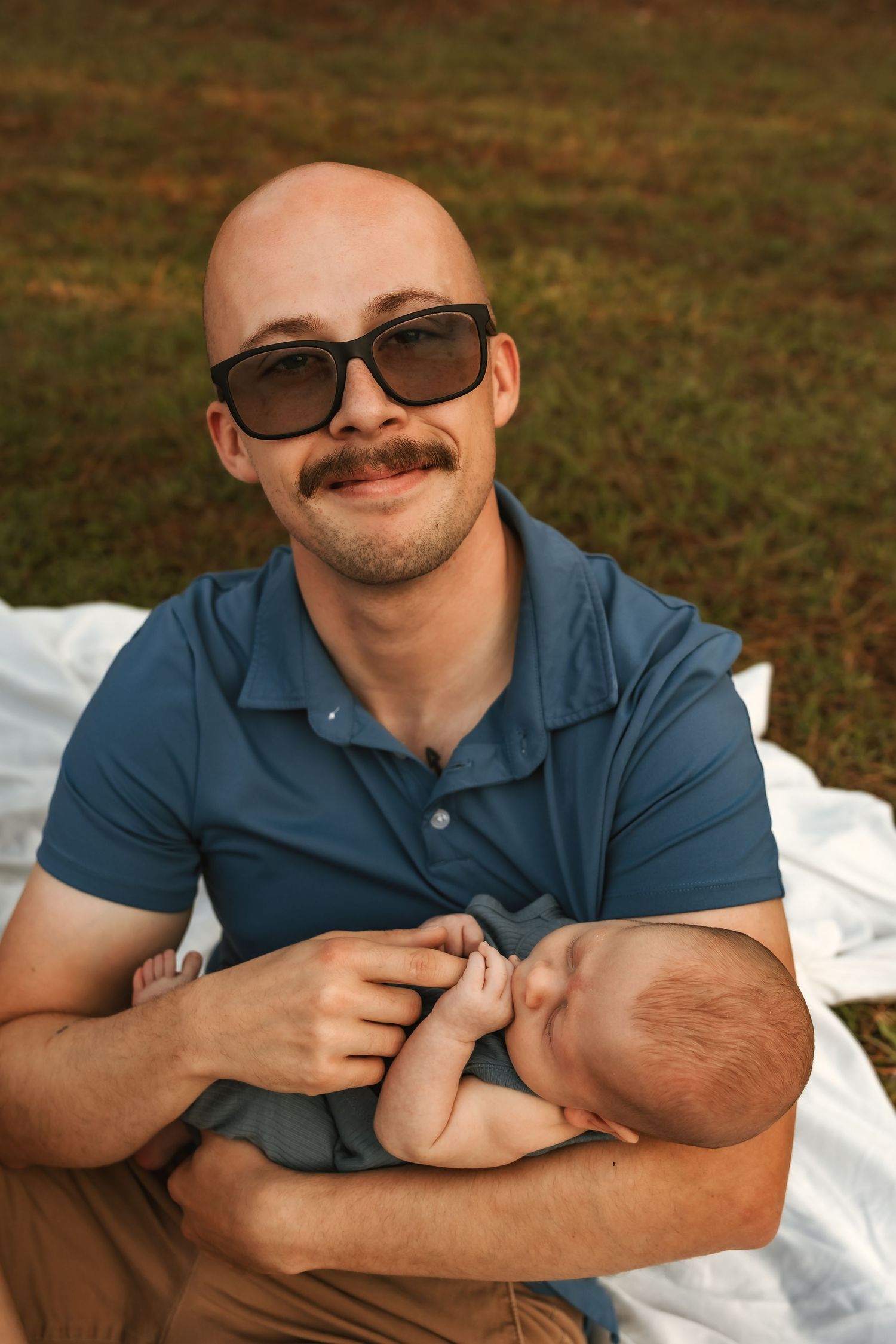 Casual outdoor photo session on blanket with blue polo shirt.