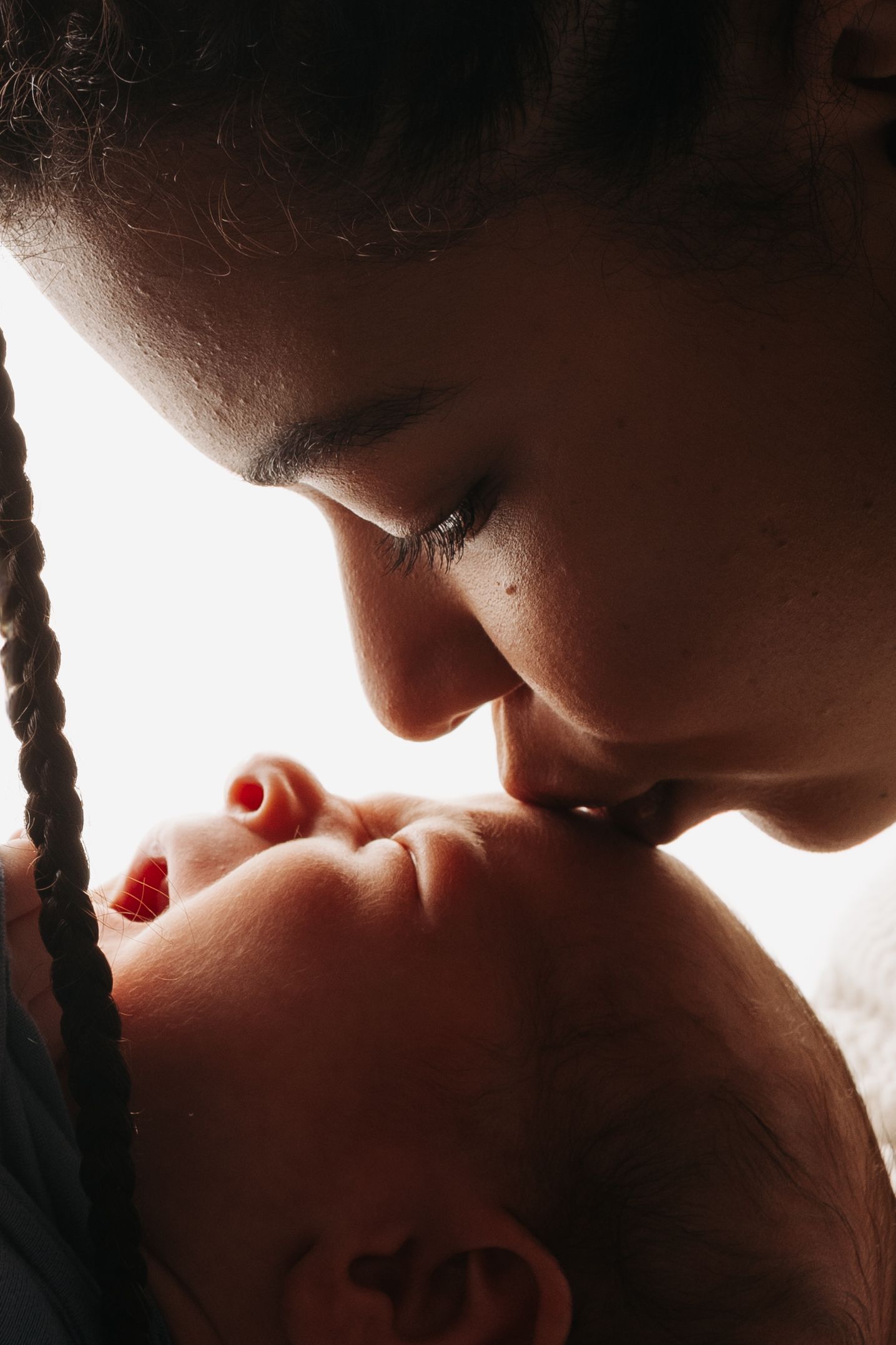 A tender moment captured in silhouette shows a close embrace between two people in warm lighting.