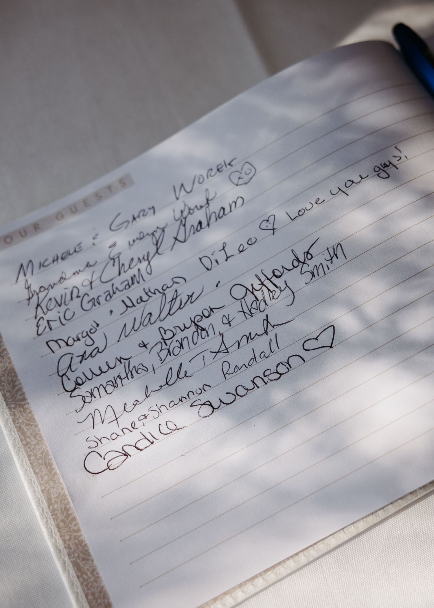 A wedding guest book open to a page filled with handwritten signatures and heartfelt messages from attendees.