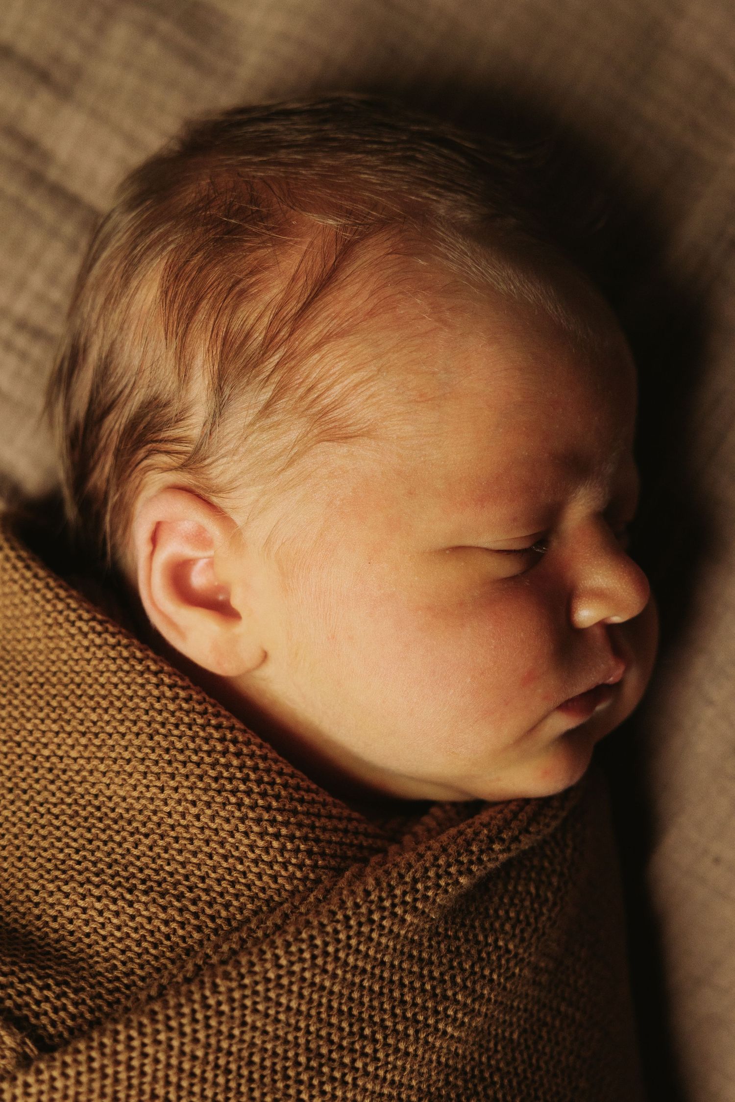 Close-up progression of a sleeping newborn baby swaddled in a brown knit blanket captured from different angles.