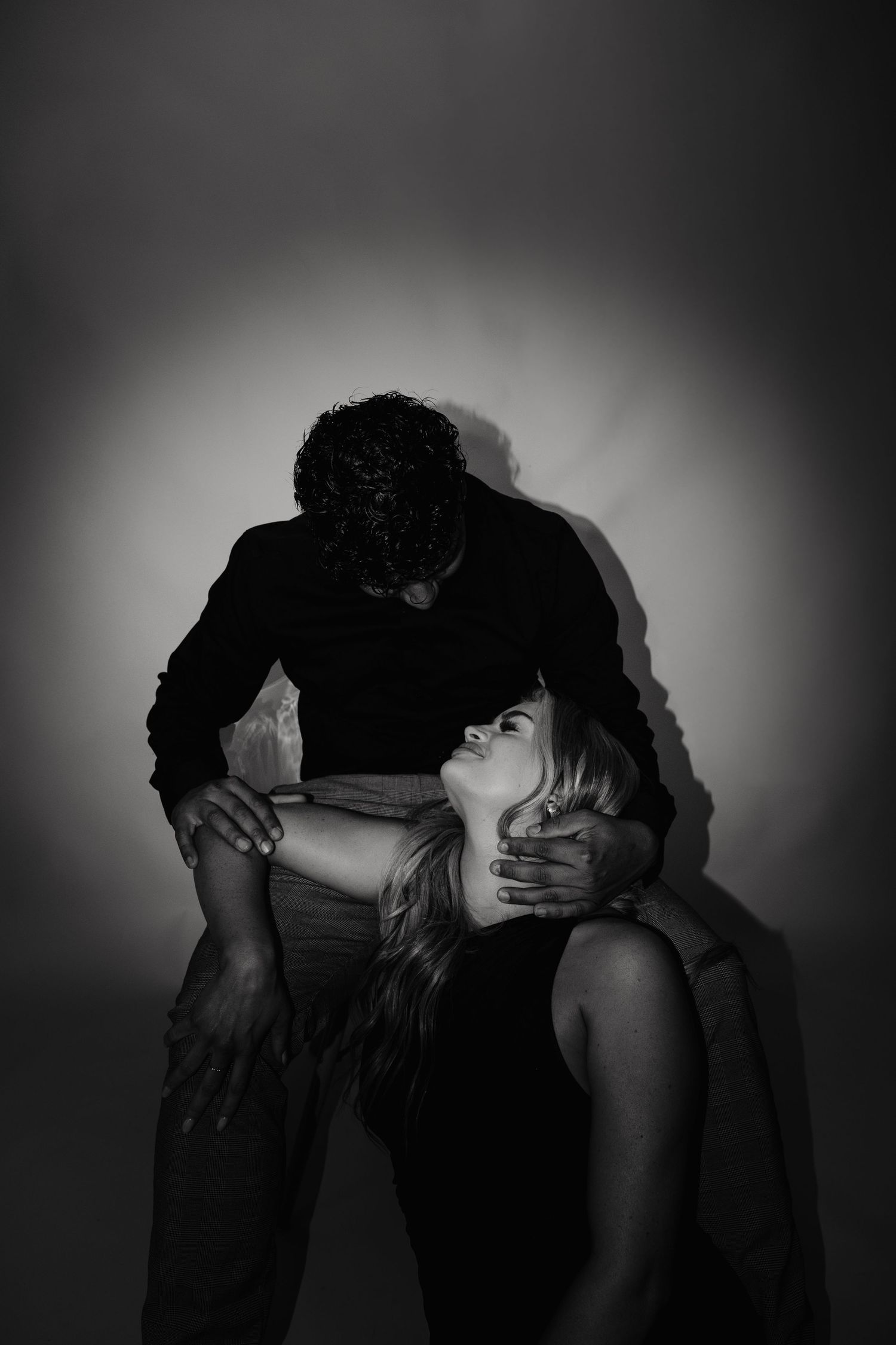 Dramatic black and white photo series showing silhouetted figures in intimate poses against dark backgrounds.