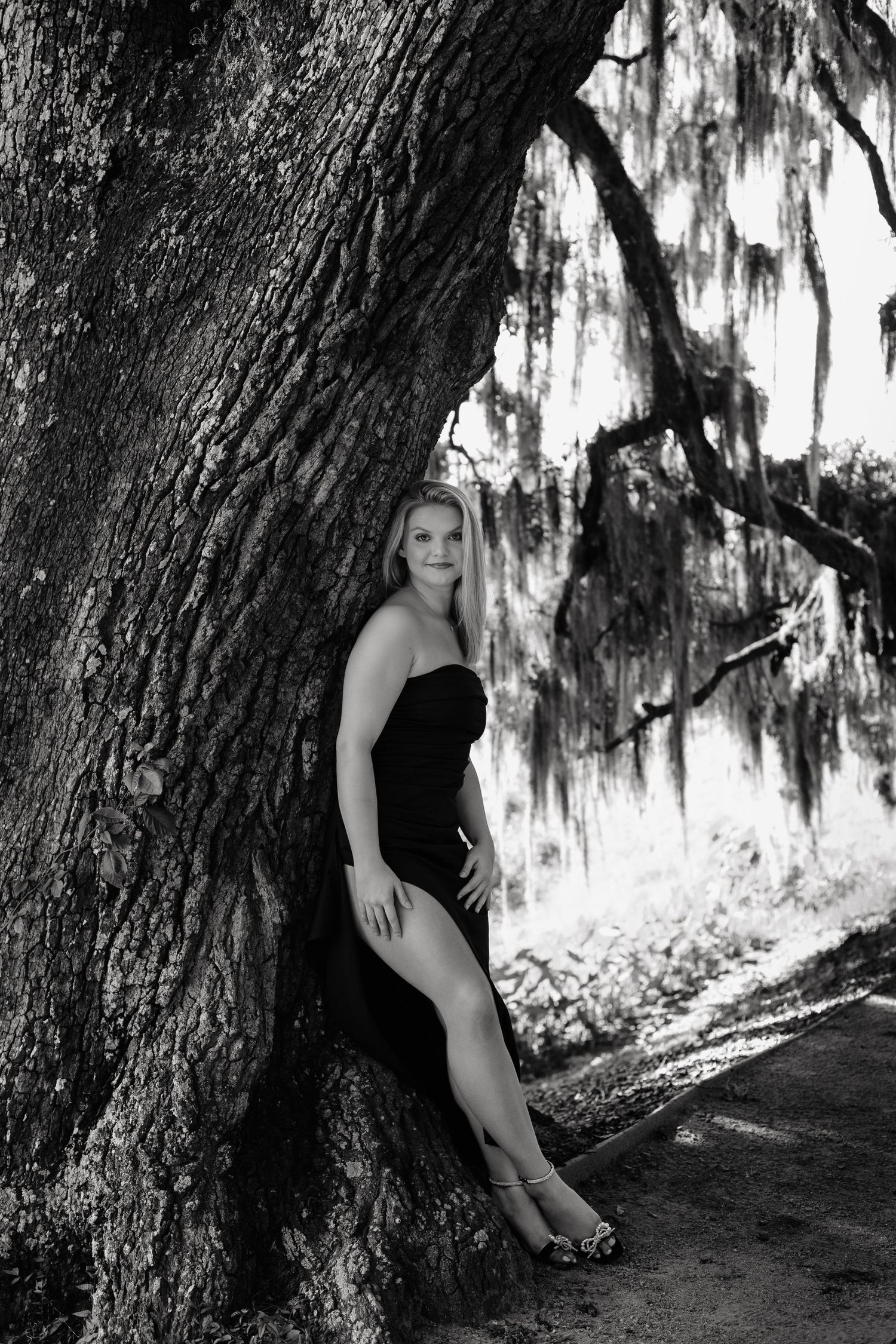 A sequence of artistic black and white portraits captured against a large tree in a moody forest setting.