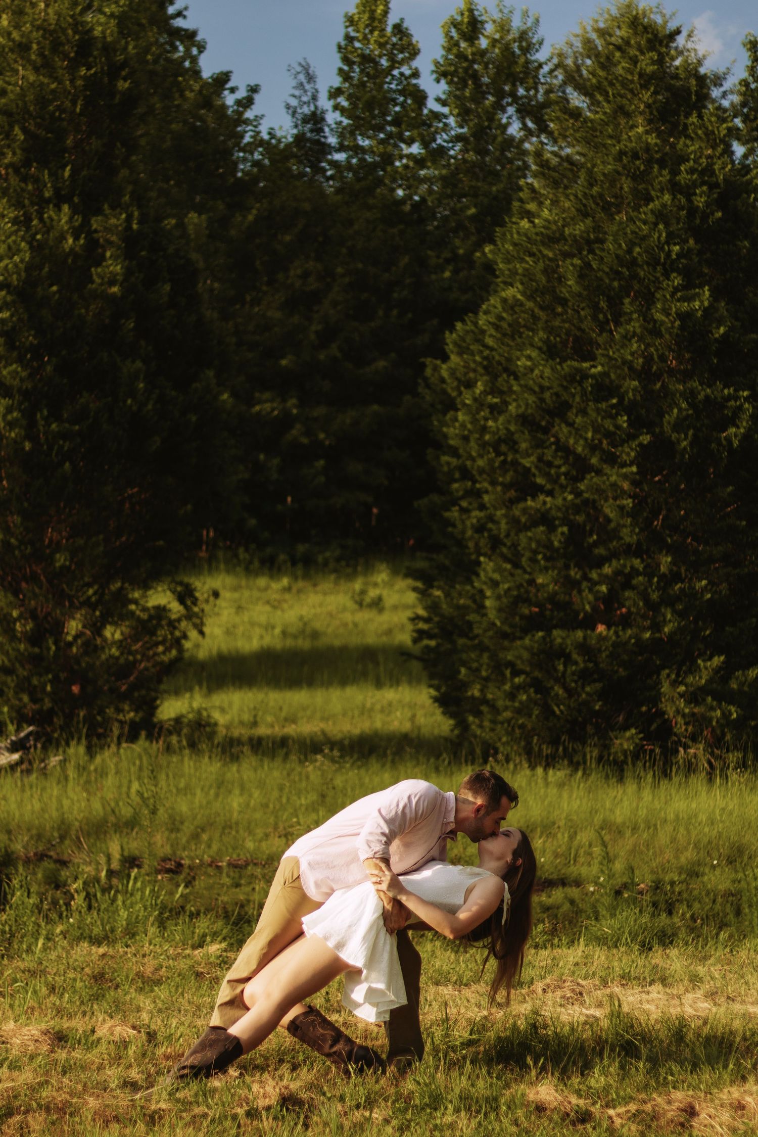 Couple relaxes together in a scenic meadow surrounded by evergreen trees on a sunny summer afternoon.