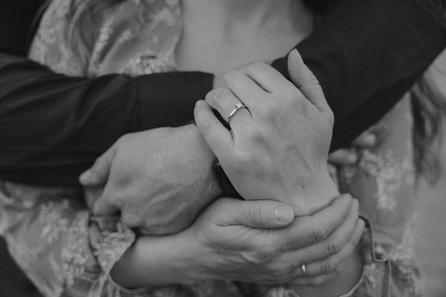 A sequence of black and white close-up shots showing hands holding a small object with delicate care.