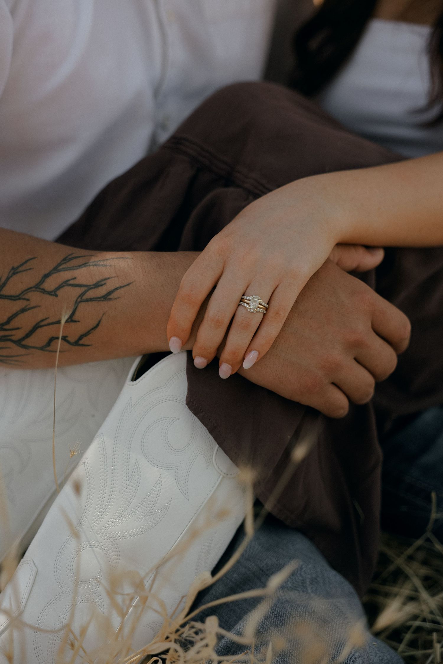 Close-up view of hands wearing a silver ring and showing a nature-inspired branch tattoo design on the forearm.