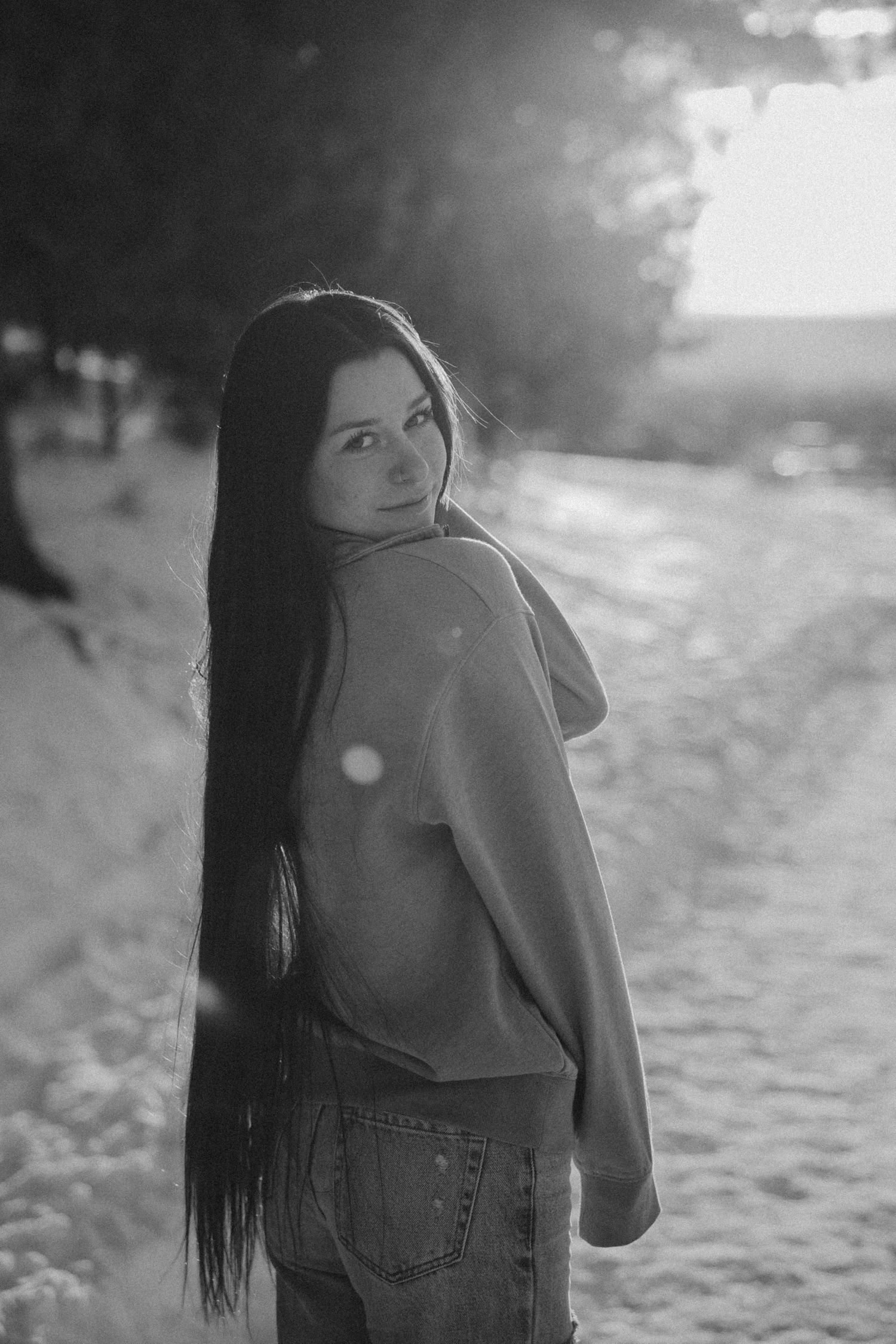 Black and white portrait of a person in denim jacket with backlit bokeh effects.