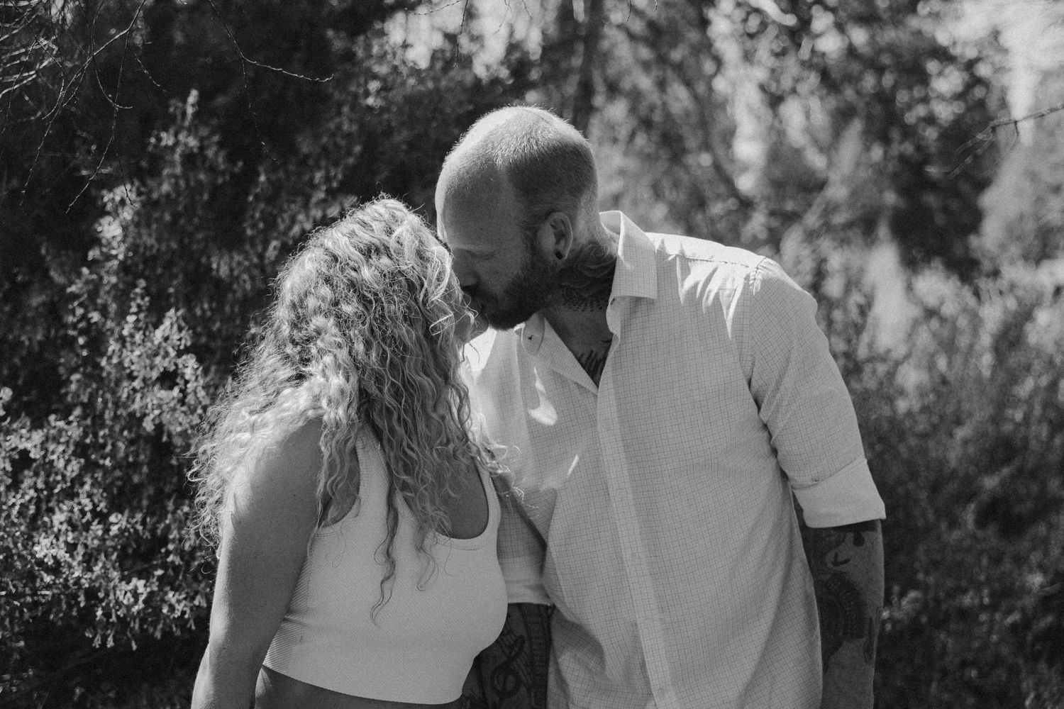 Couple sharing tender moments outdoors in natural lighting.