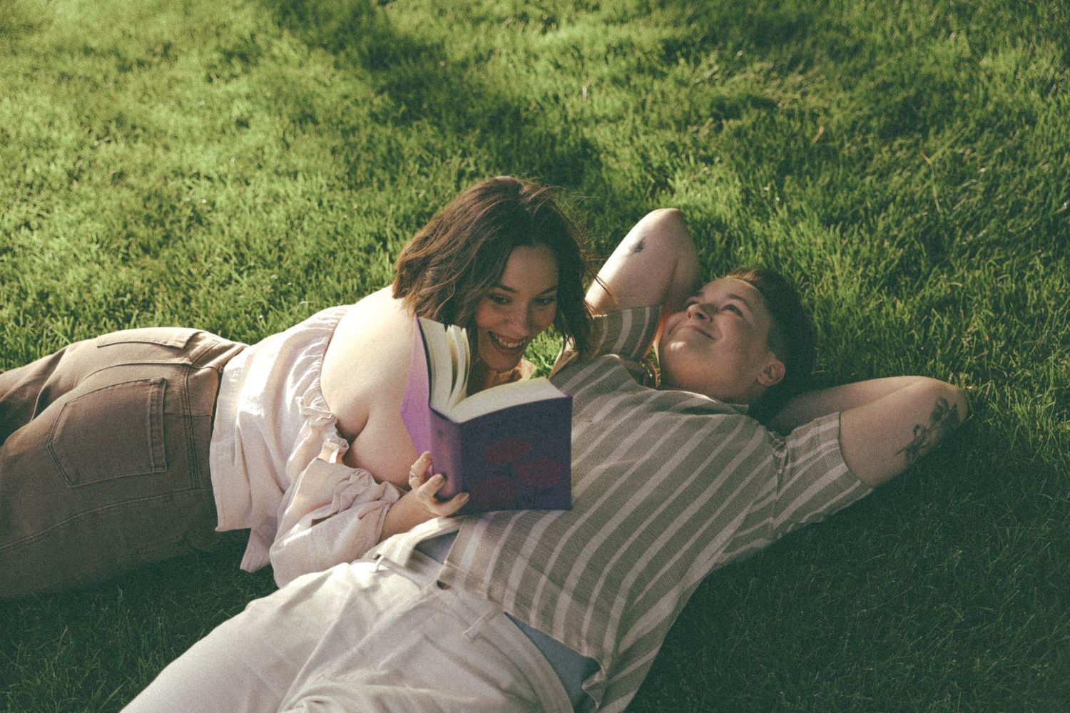 Couple laying together on grass during a warm summer afternoon.