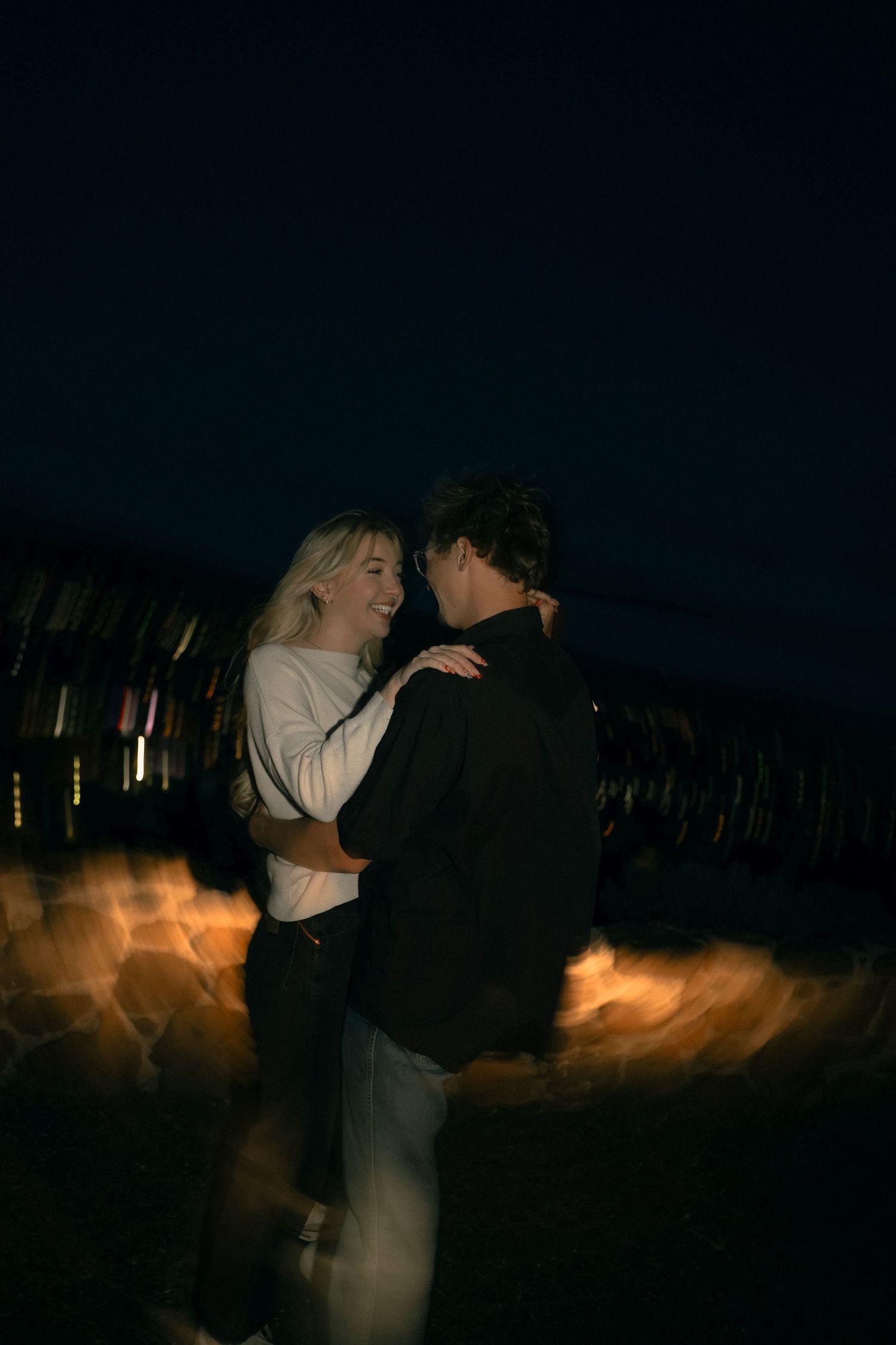 A couple dancing together at night with blurred lights in the background.