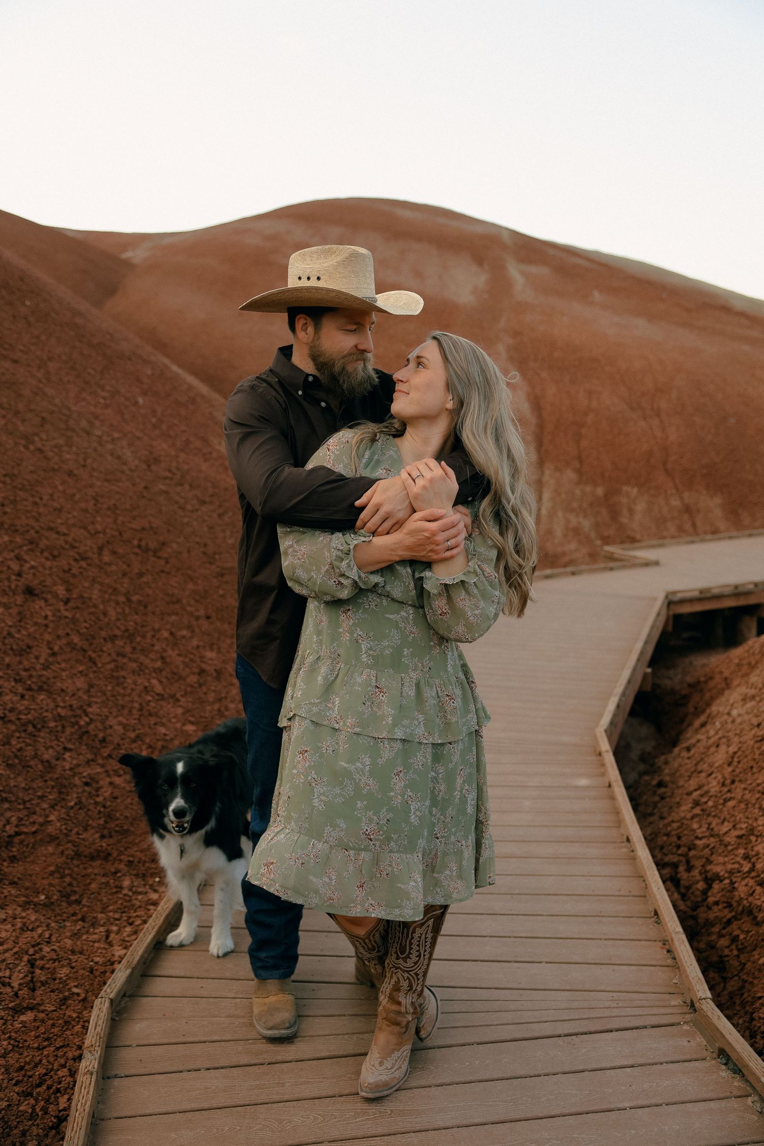 Romantic sequence on wooden boardwalk with desert mountains in background.