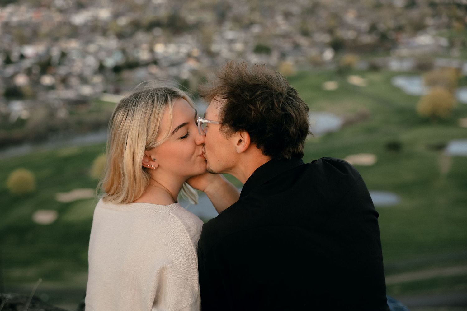 A tender moment shared between a couple with a scenic valley view in the background.