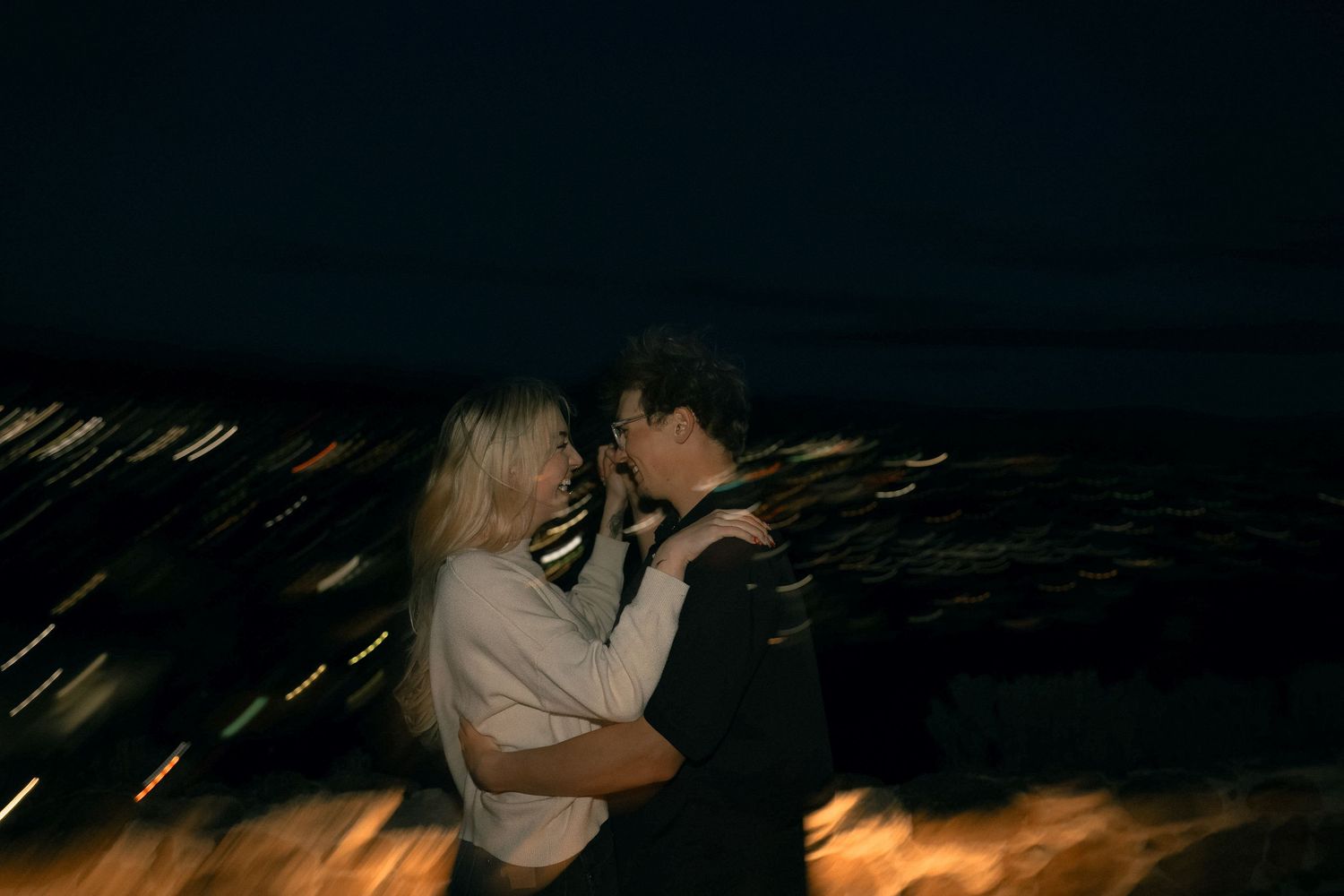A romantic couple embracing against a dark background with streaking lights.