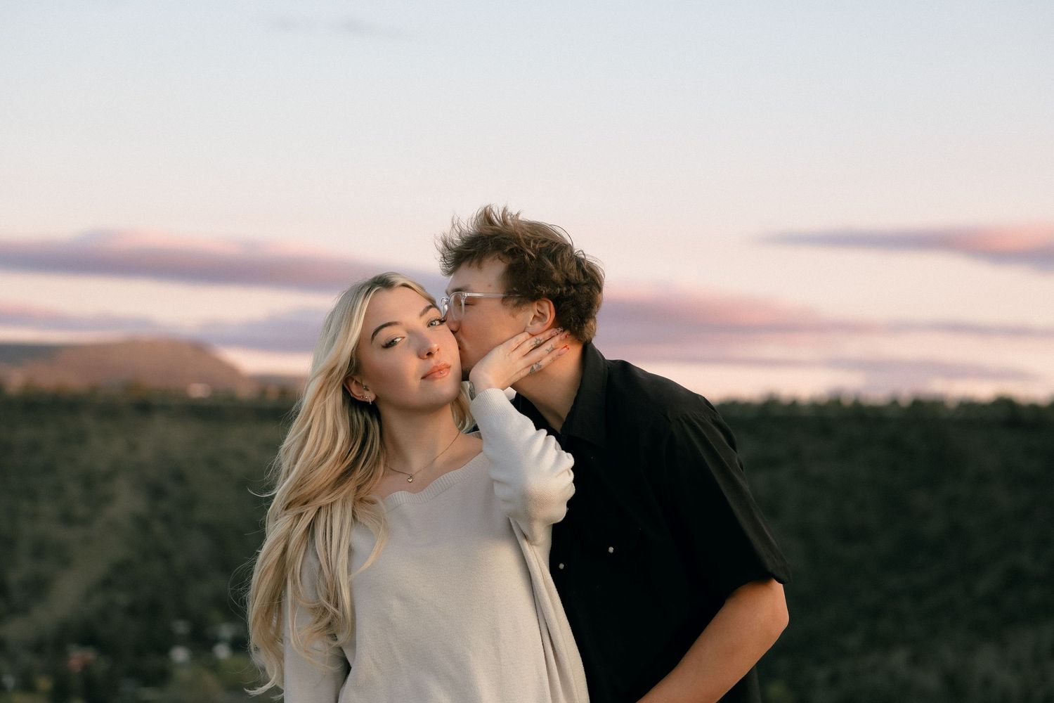 A romantic sunset moment between partners against a dusky mountain backdrop.