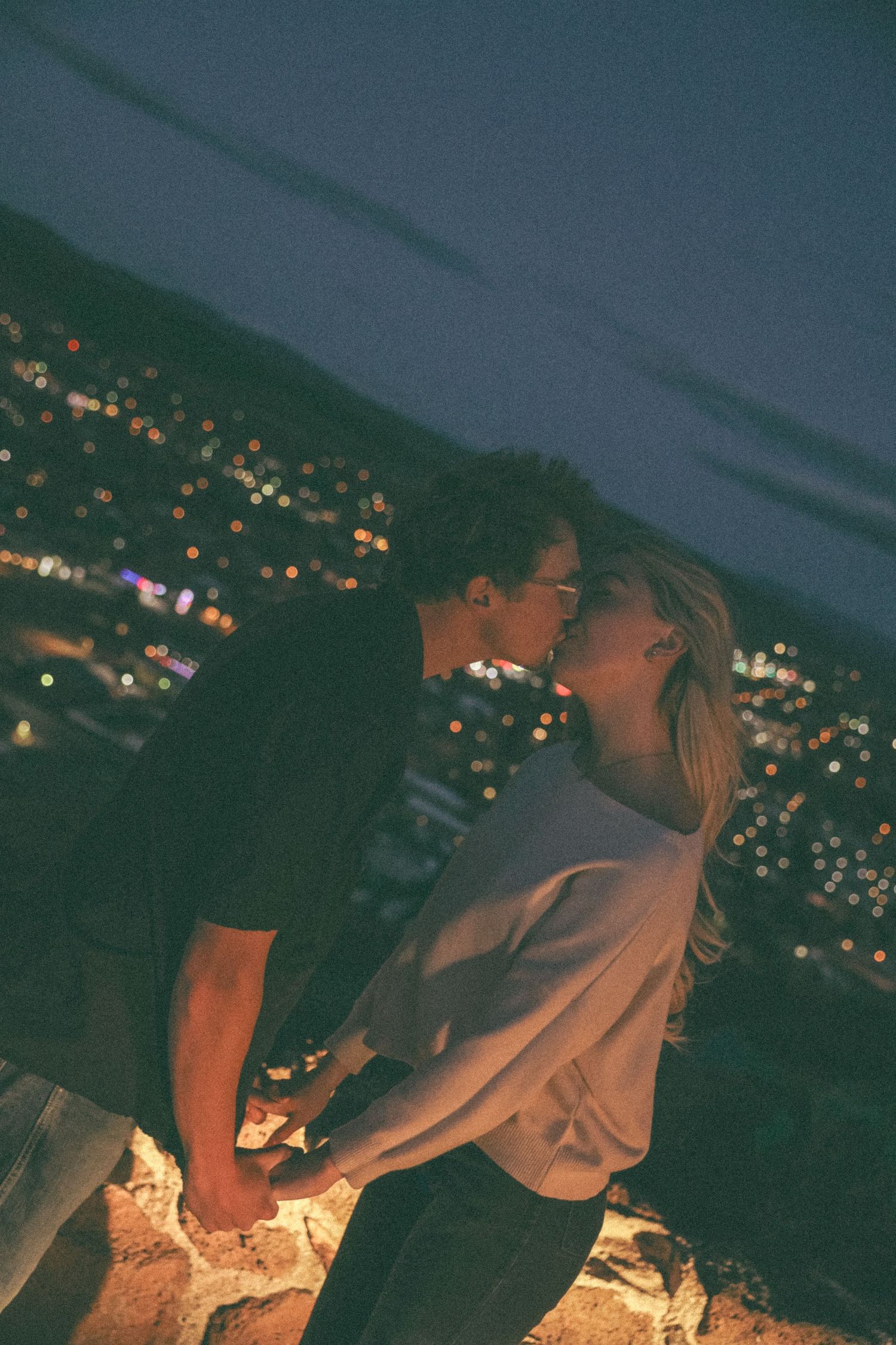 A romantic moment shared between a couple overlooking city lights at night.