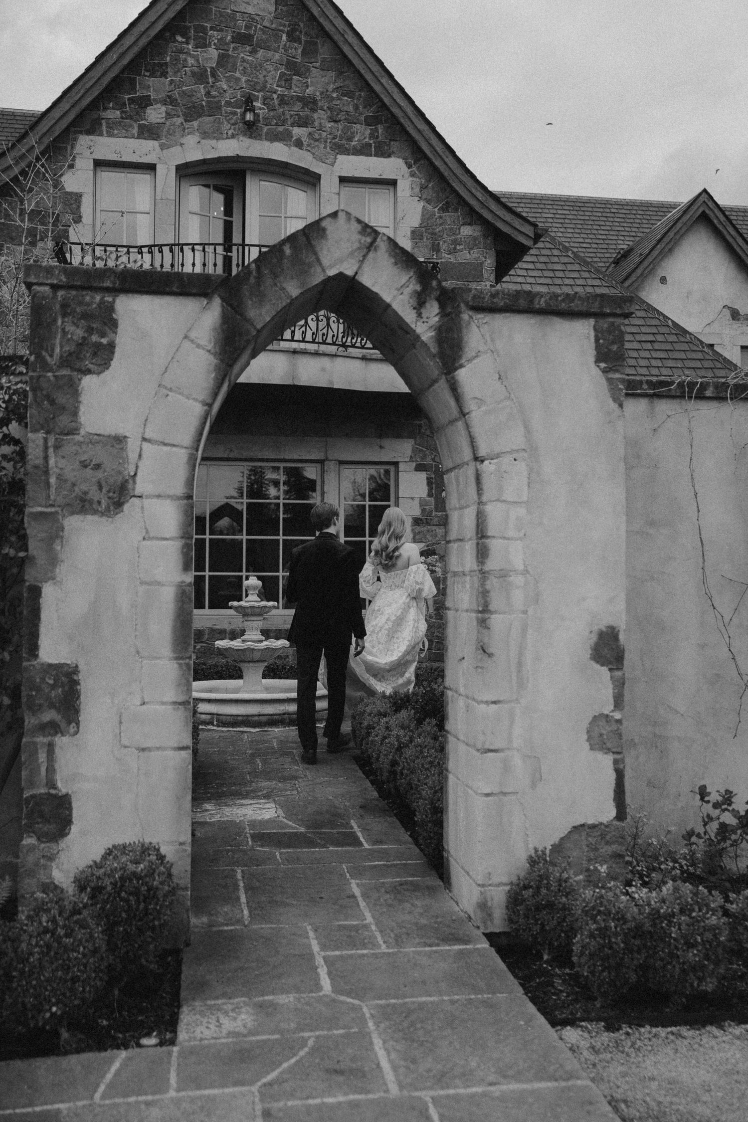 Stone archway entrance with flagstone path at a rustic building.