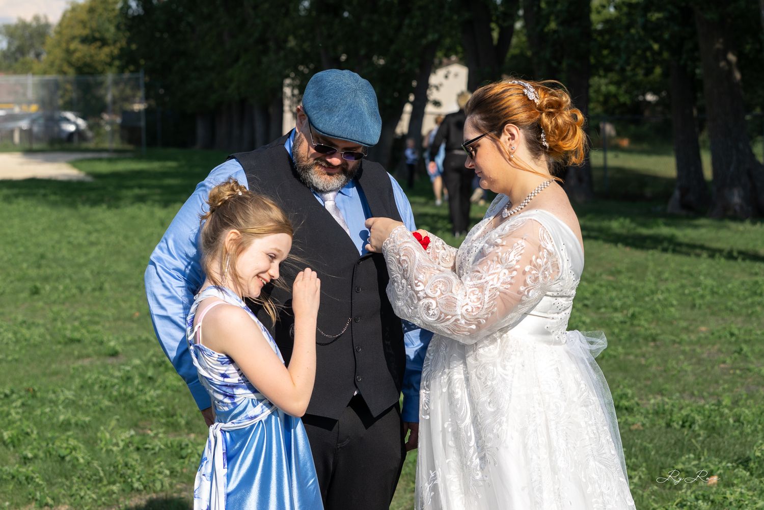Emotional moment between wedding group in blue and white attire outdoors.