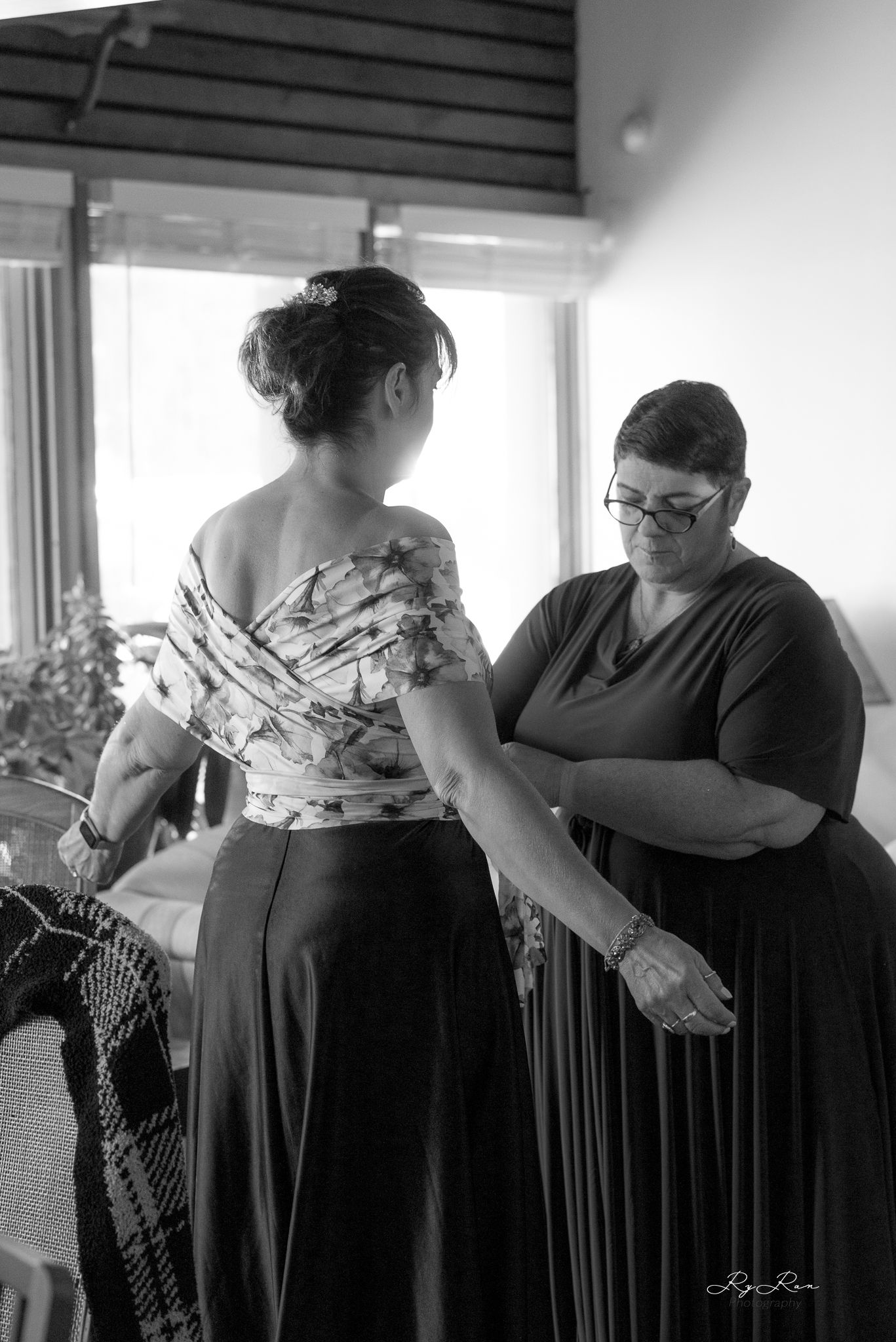 Black and white image of two people in formal attire during wedding preparations.