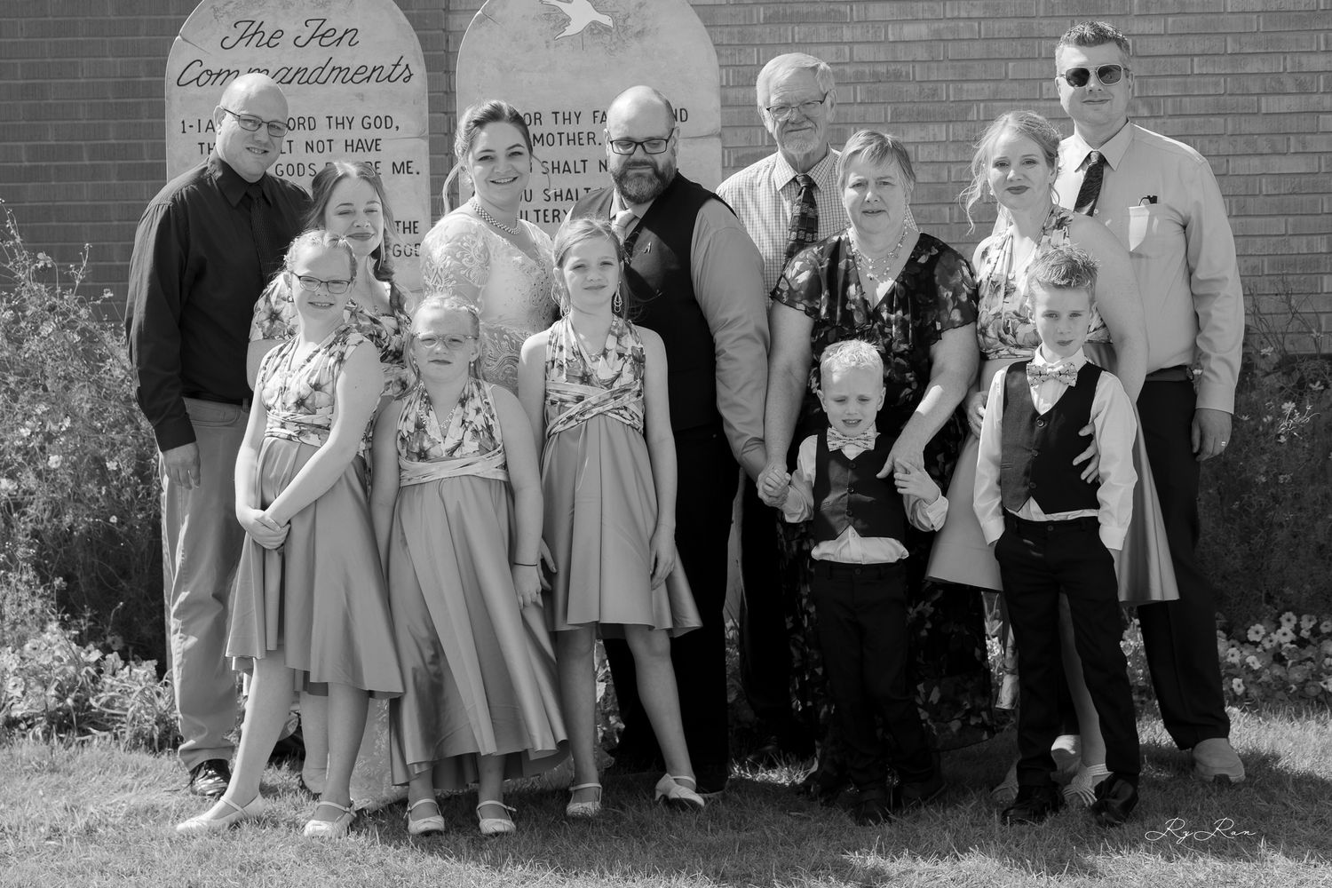 A large wedding party group photo in front of the Ten Commandments stone tablets.