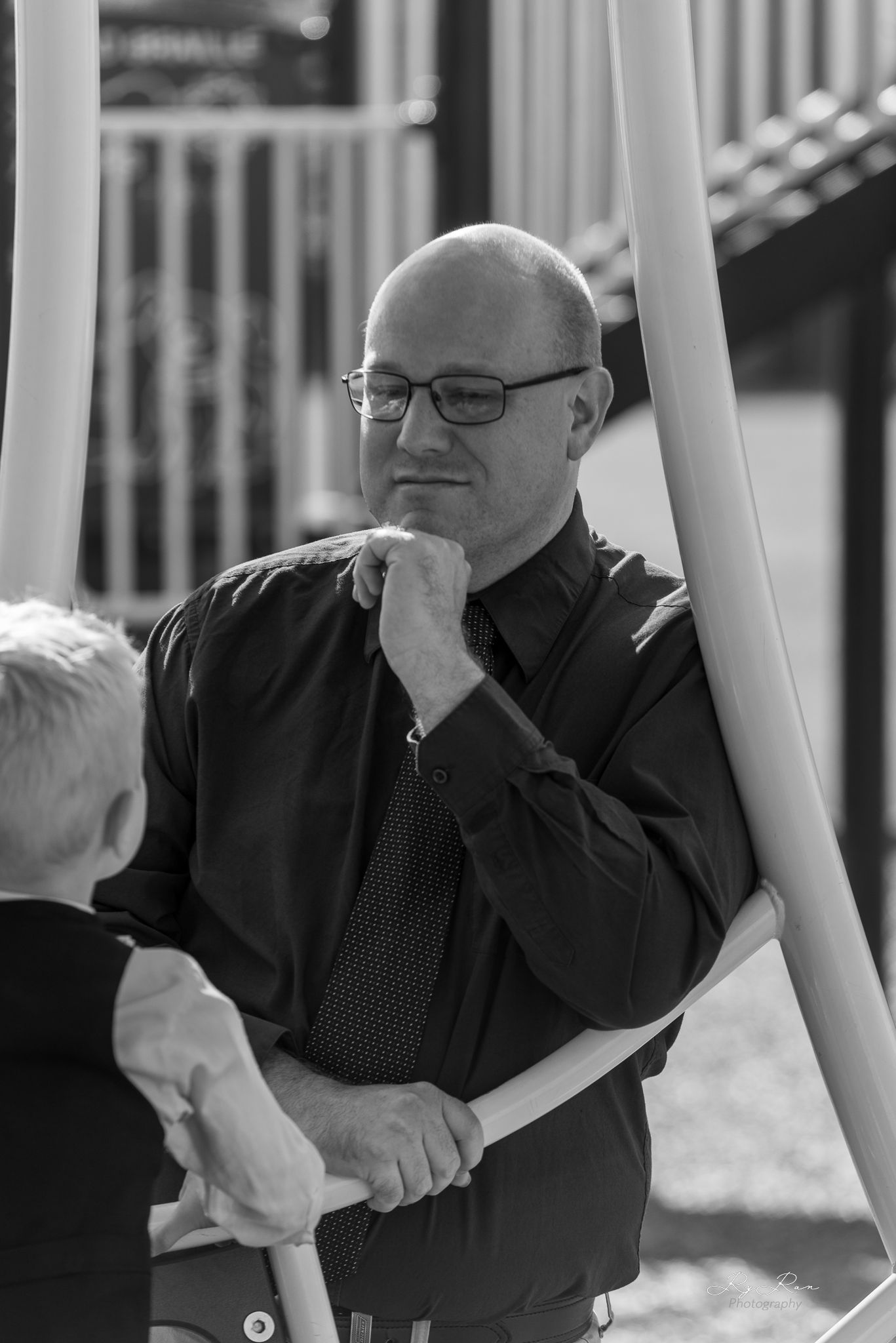 Black and white portrait of a thoughtful person in formal wear at a playground.