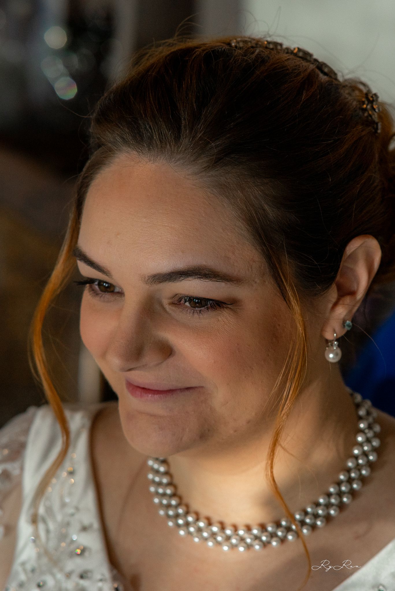 Close up of a bride wearing pearl jewelry and lace dress while getting ready for her wedding.