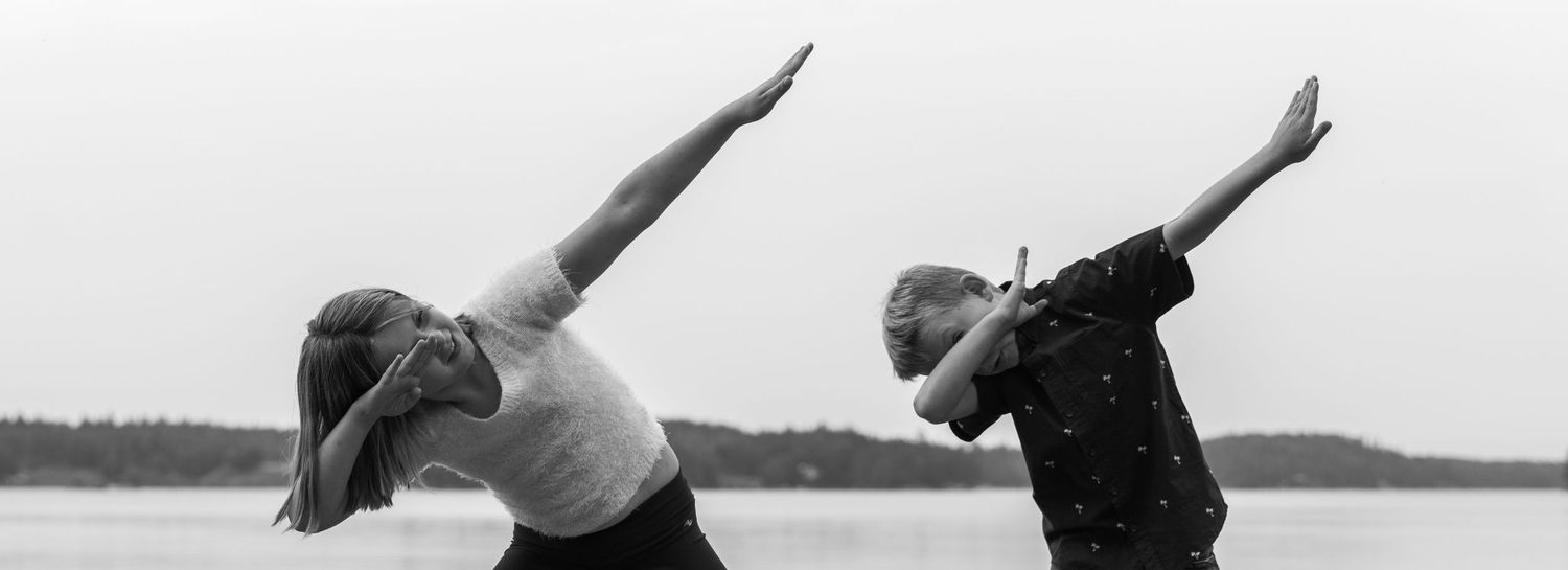 Two people practicing yoga side by side on a dock with matching poses.