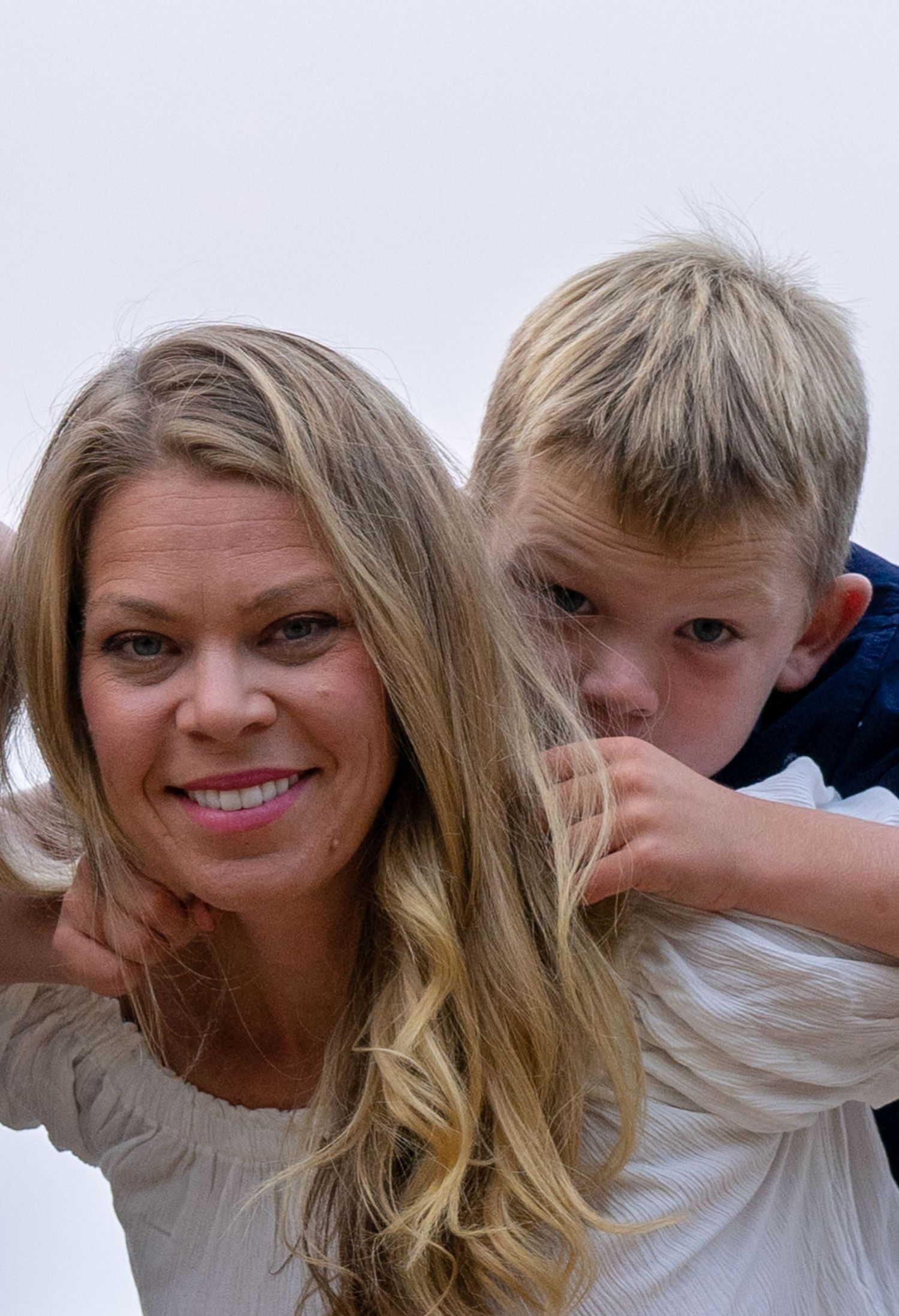 A playful family moment captured outdoors with long blonde hair and a happy expression.