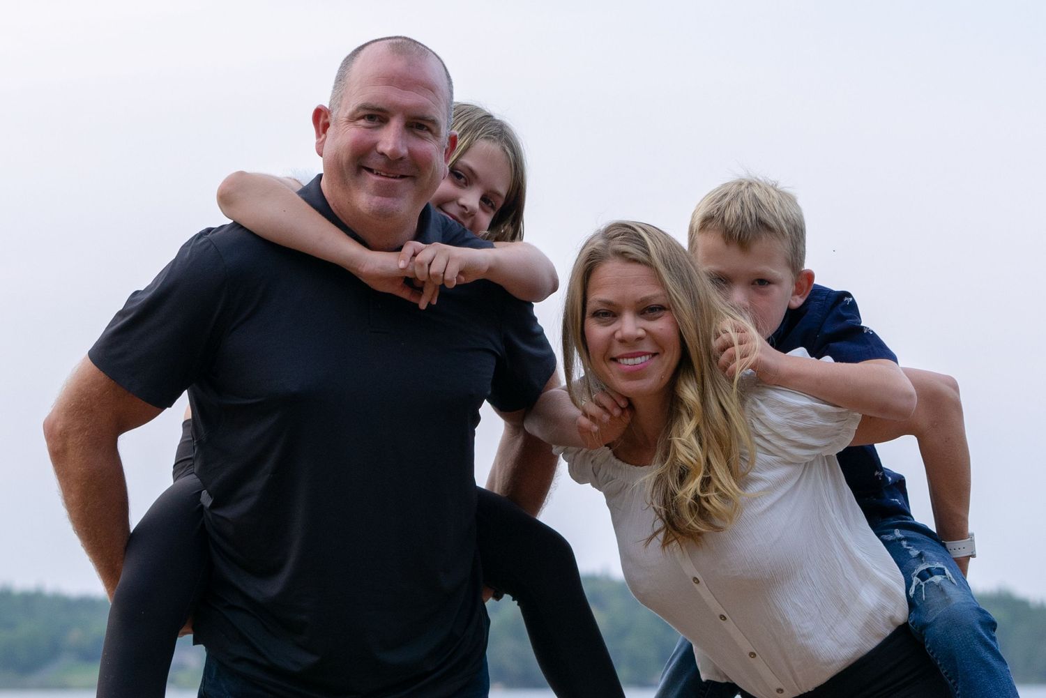 Playful family portrait outdoors with natural scenery in background.