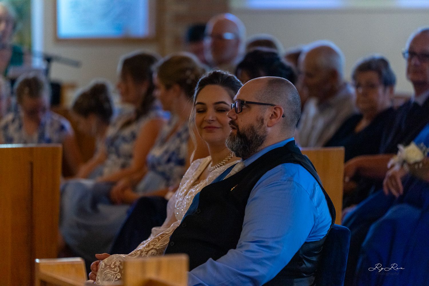 Wedding guests seated in church pews during the ceremony.
