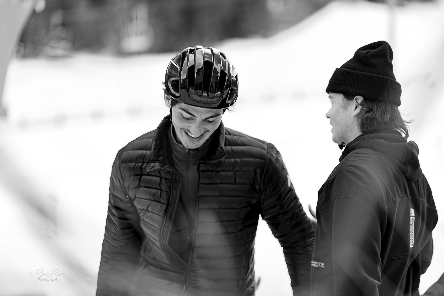 Two people having a friendly conversation while wearing winter gear in snowy conditions.