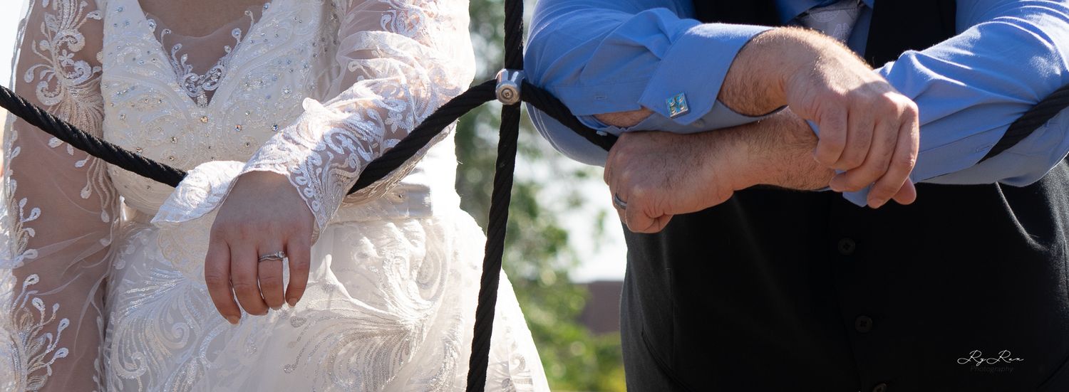 Two people stand close together during an outdoor wedding ceremony.