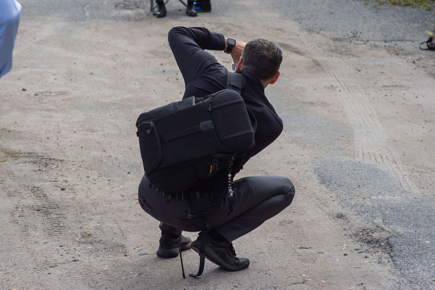 Five sequential photos show a person in dark clothing crouching down by a gravel path to take photographs.
